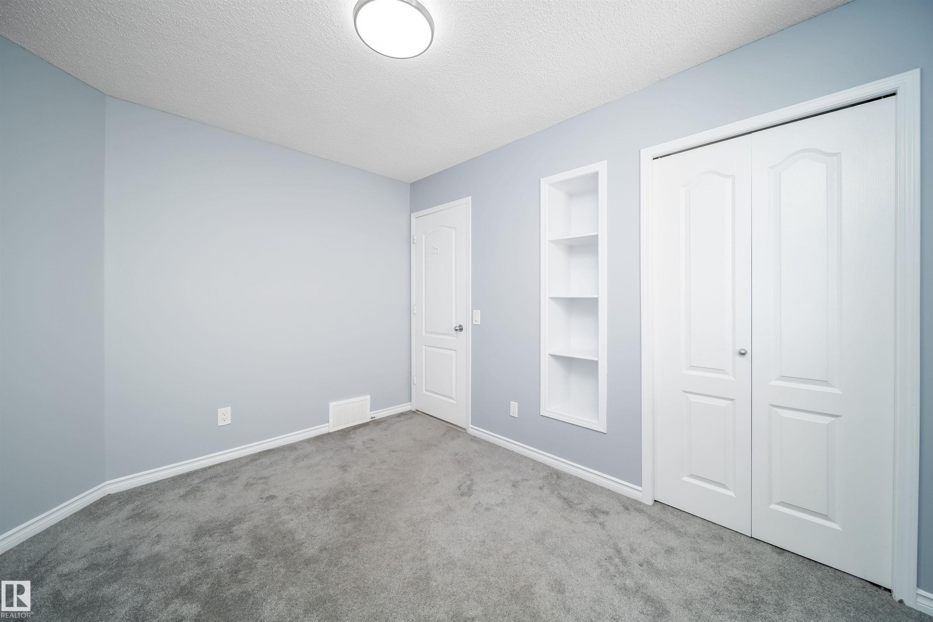 Gray carpeting, light blue wall paint, white trim, recessed shelving, and a bi-fold closet door - 7848 7 Avenue Sw, Edmonton, AB