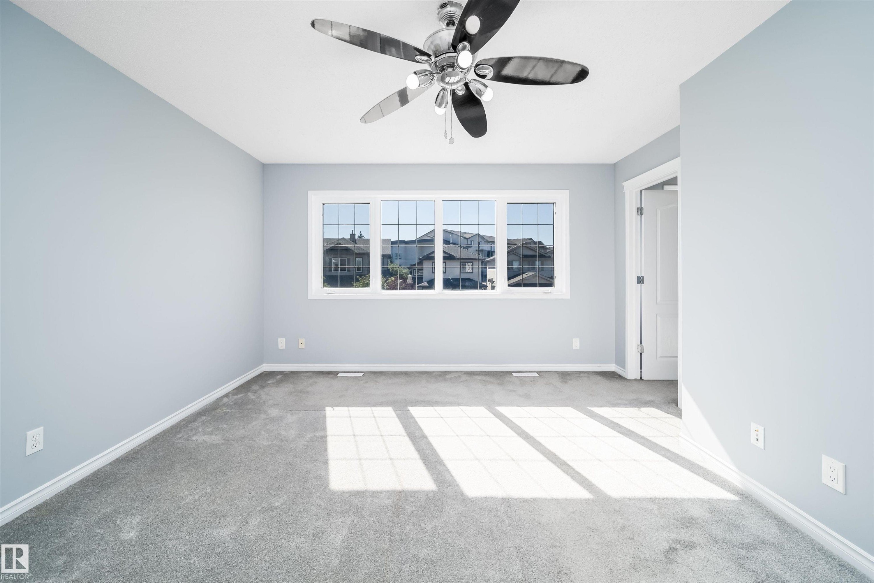 Wall-to-wall carpeting, multiple pane window, ceiling fan with integrated lighting, and painted walls - 7848 7 Avenue Sw, Edmonton, AB