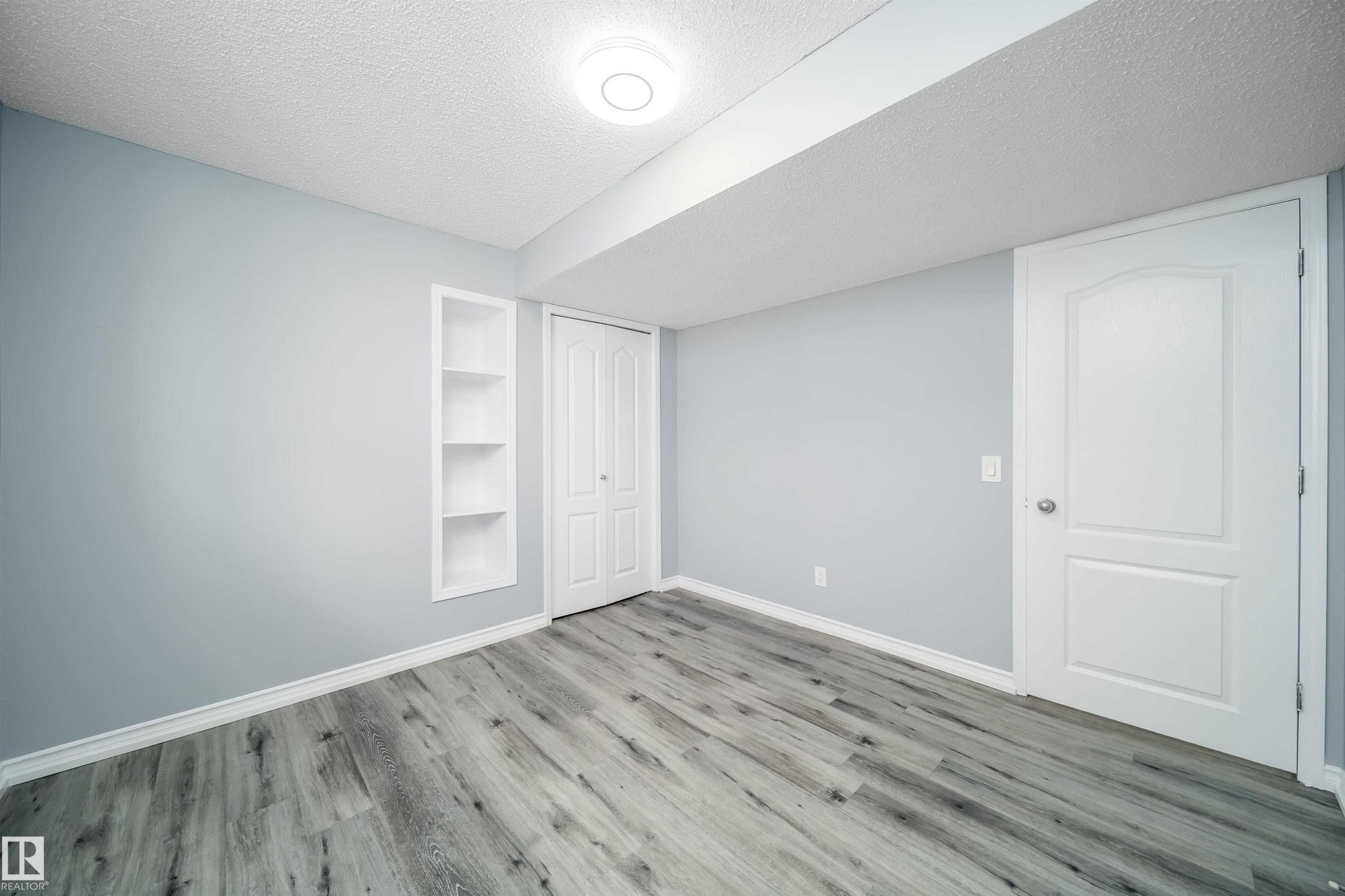 Wood-finish flooring, recessed shelving, modern ceiling light fixture, white trim, and solid panel doors - 7848 7 Avenue Sw, Edmonton, AB