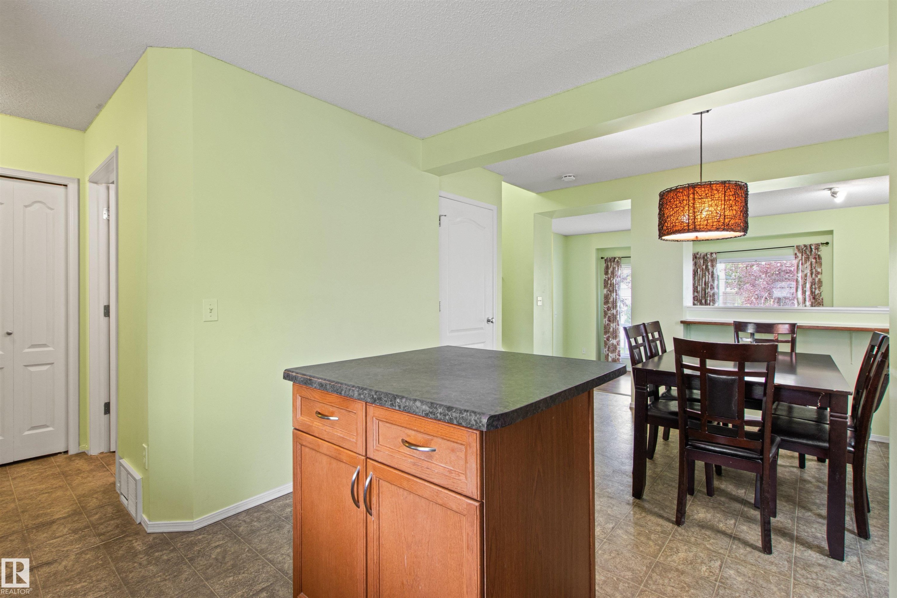 Kitchen island with wood-finish cabinetry and a dark countertop - 9118 Scott Crescent Nw, Edmonton, AB - Indoor Photo Showing Dining Room
