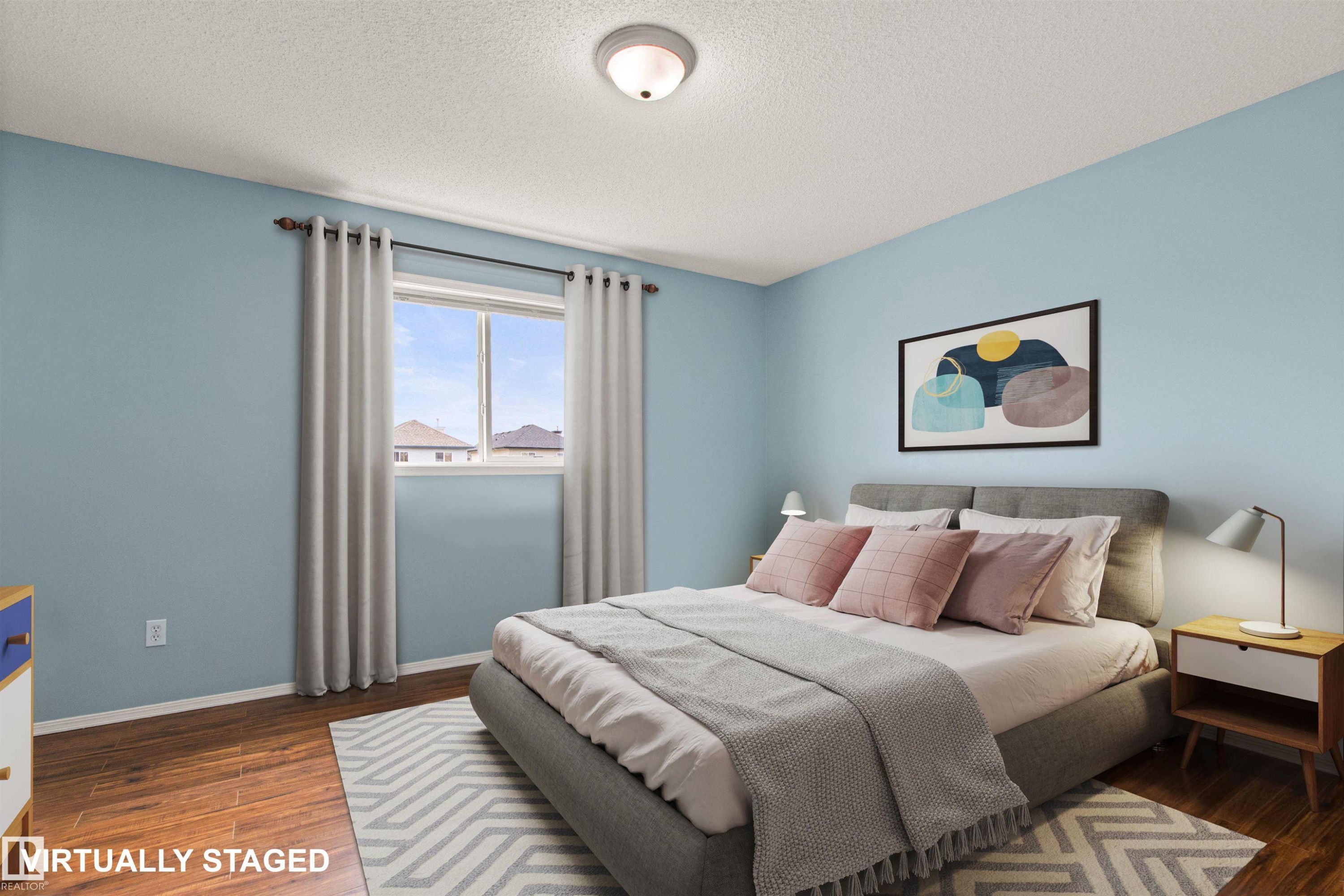 Wood-finish flooring, light blue wall paint, and a window with roller shades - 9118 Scott Crescent Nw, Edmonton, AB - Indoor Photo Showing Bedroom