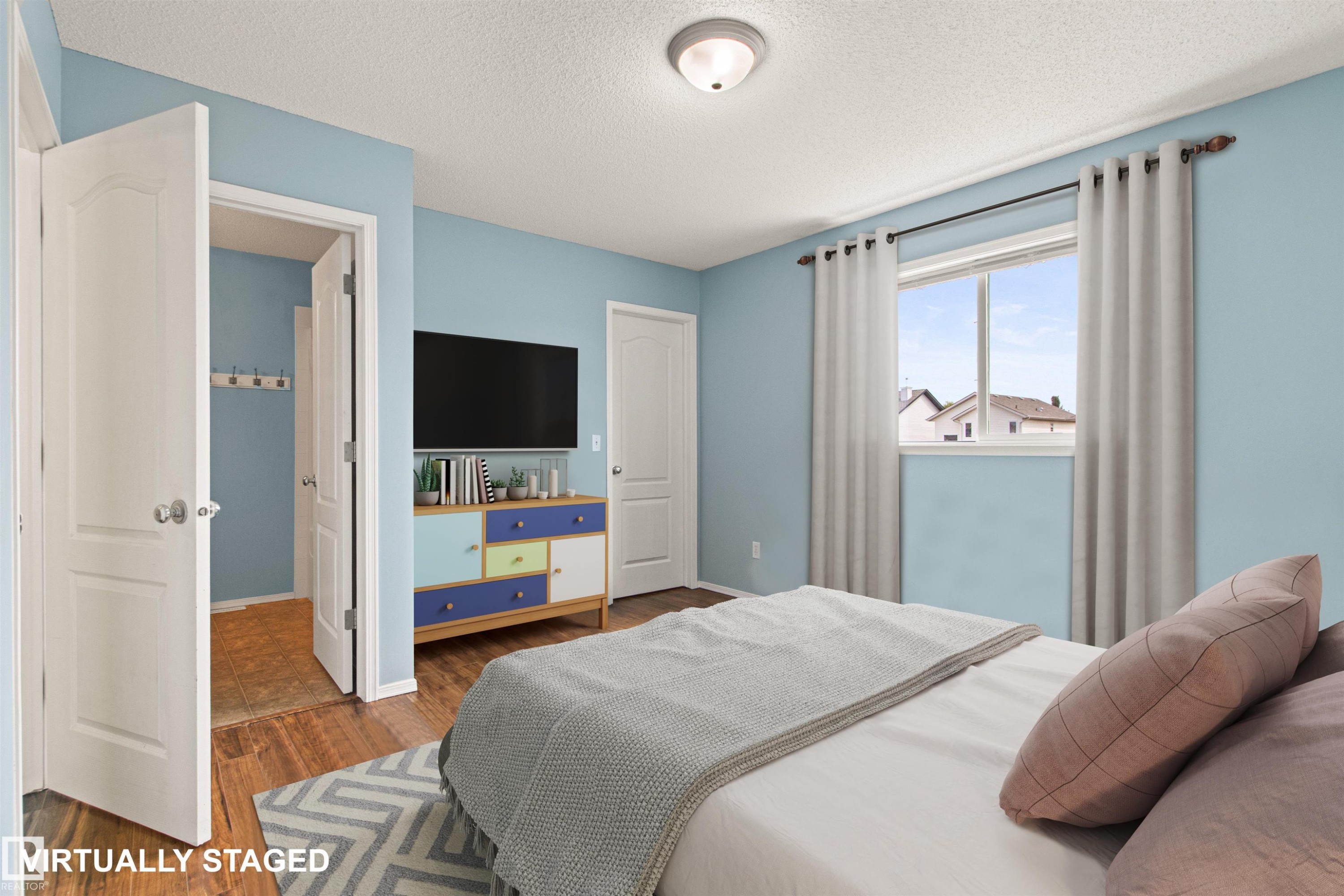 Light blue walls complement the wood-finish flooring - 9118 Scott Crescent Nw, Edmonton, AB - Indoor Photo Showing Bedroom