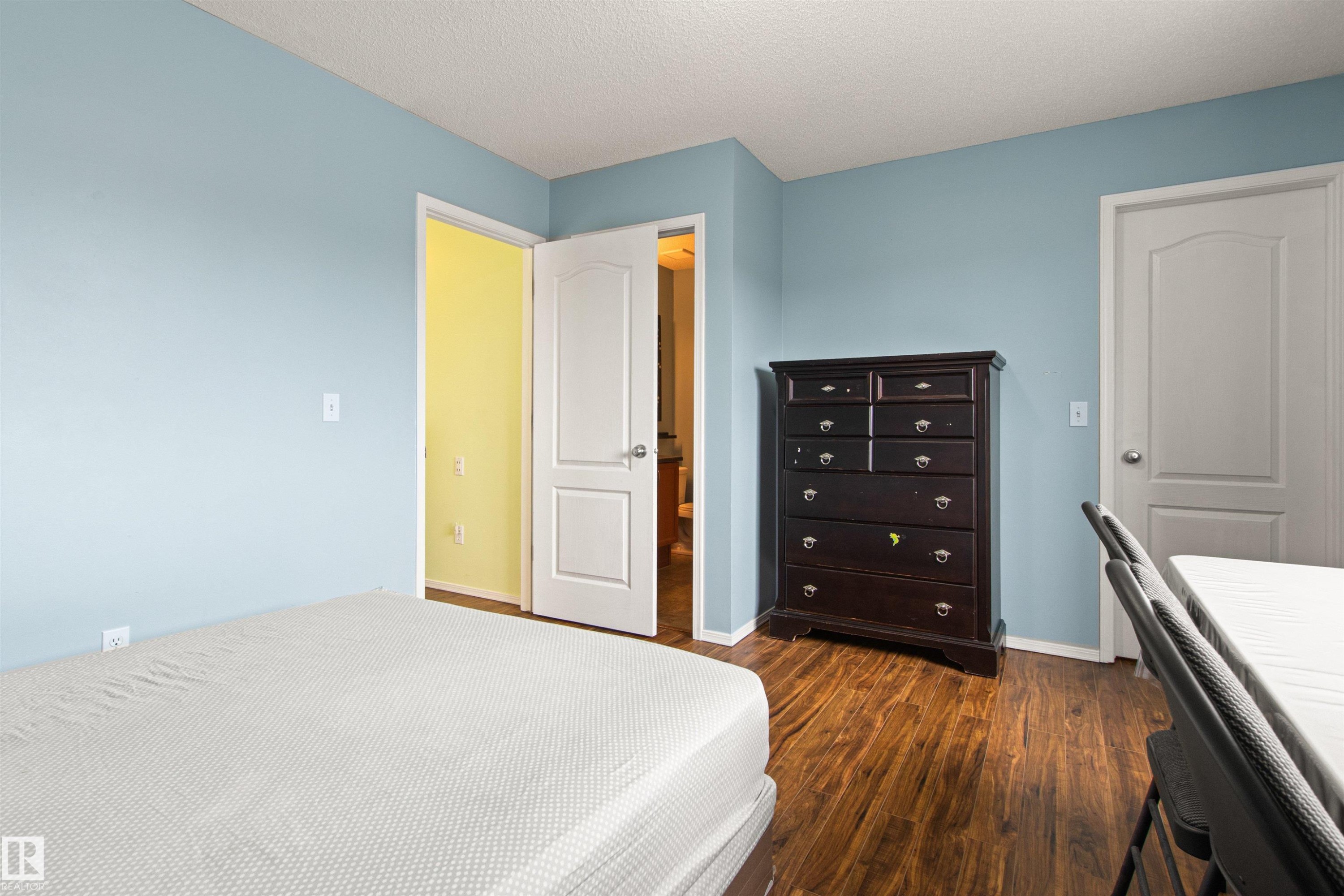 Wood-finish flooring with light blue walls and white trim - 9118 Scott Crescent Nw, Edmonton, AB - Indoor Photo Showing Bedroom