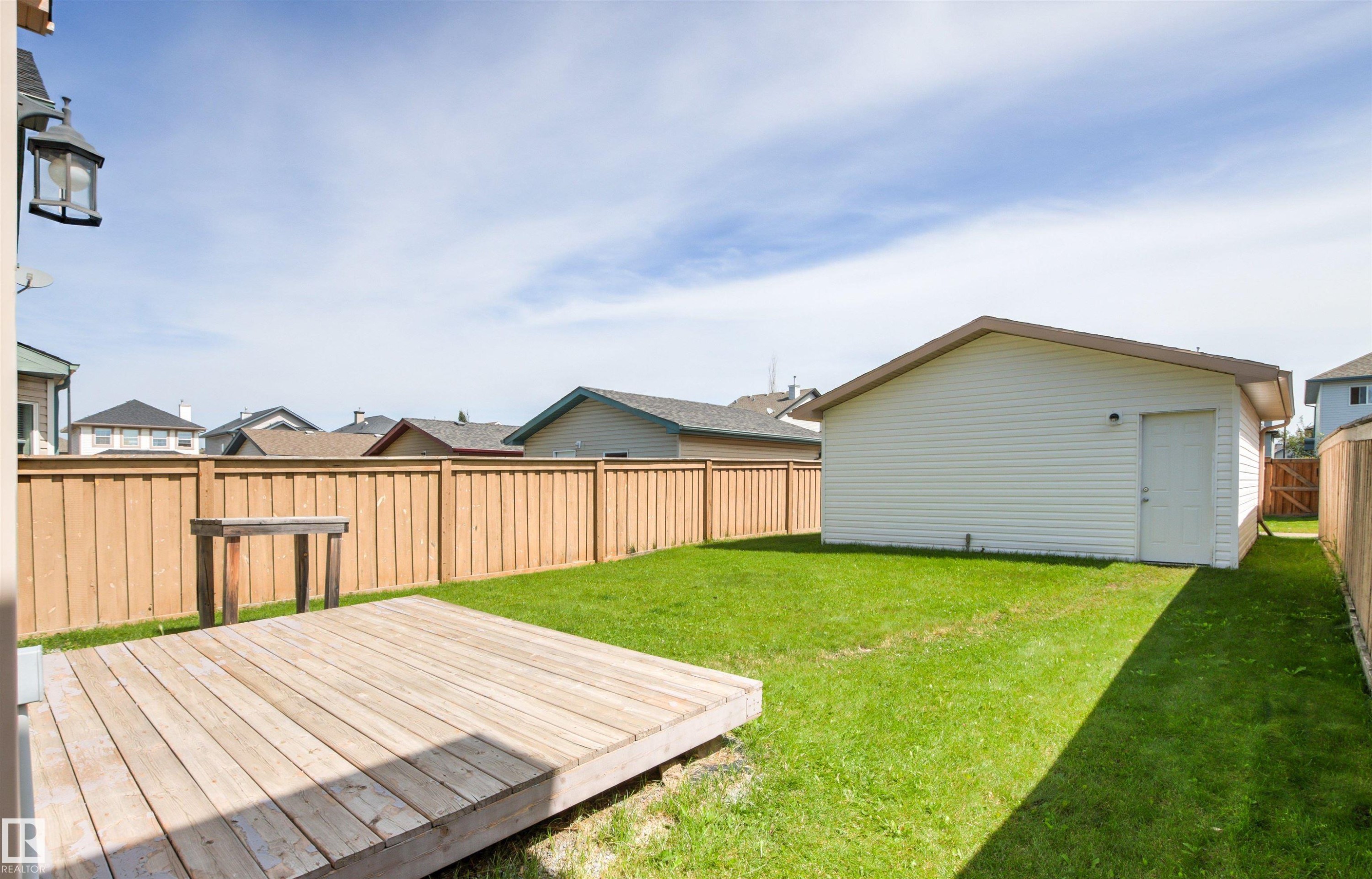 Expansive backyard featuring a wood deck, a detached structure with siding, a side entry door, and a privacy fence - 9118 Scott Crescent Nw, Edmonton, AB - Outdoor With Deck Patio Veranda With Exterior