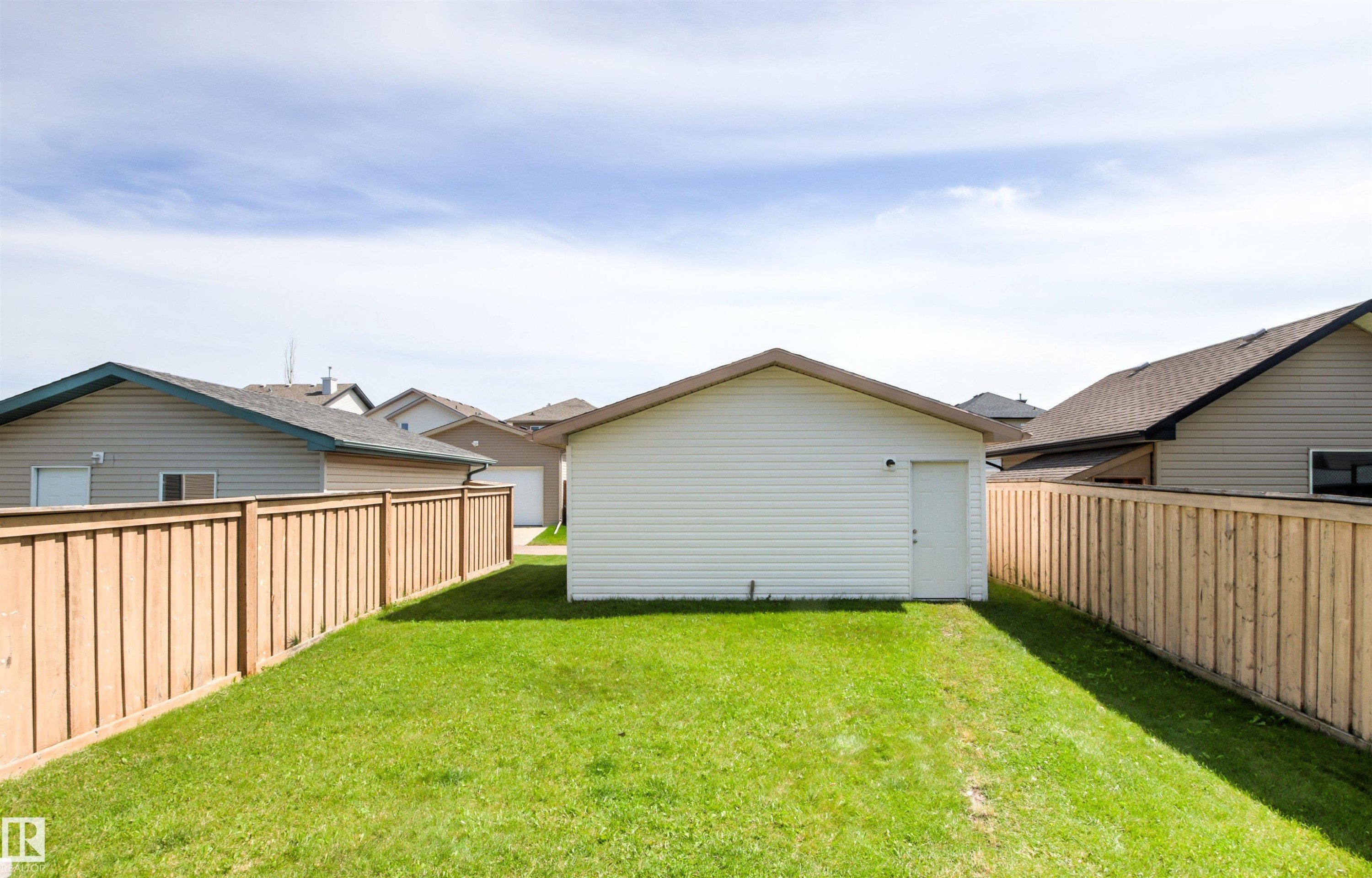 Expansive grassy yard with a detached garage and wood privacy fencing - 9118 Scott Crescent Nw, Edmonton, AB - Outdoor With Exterior