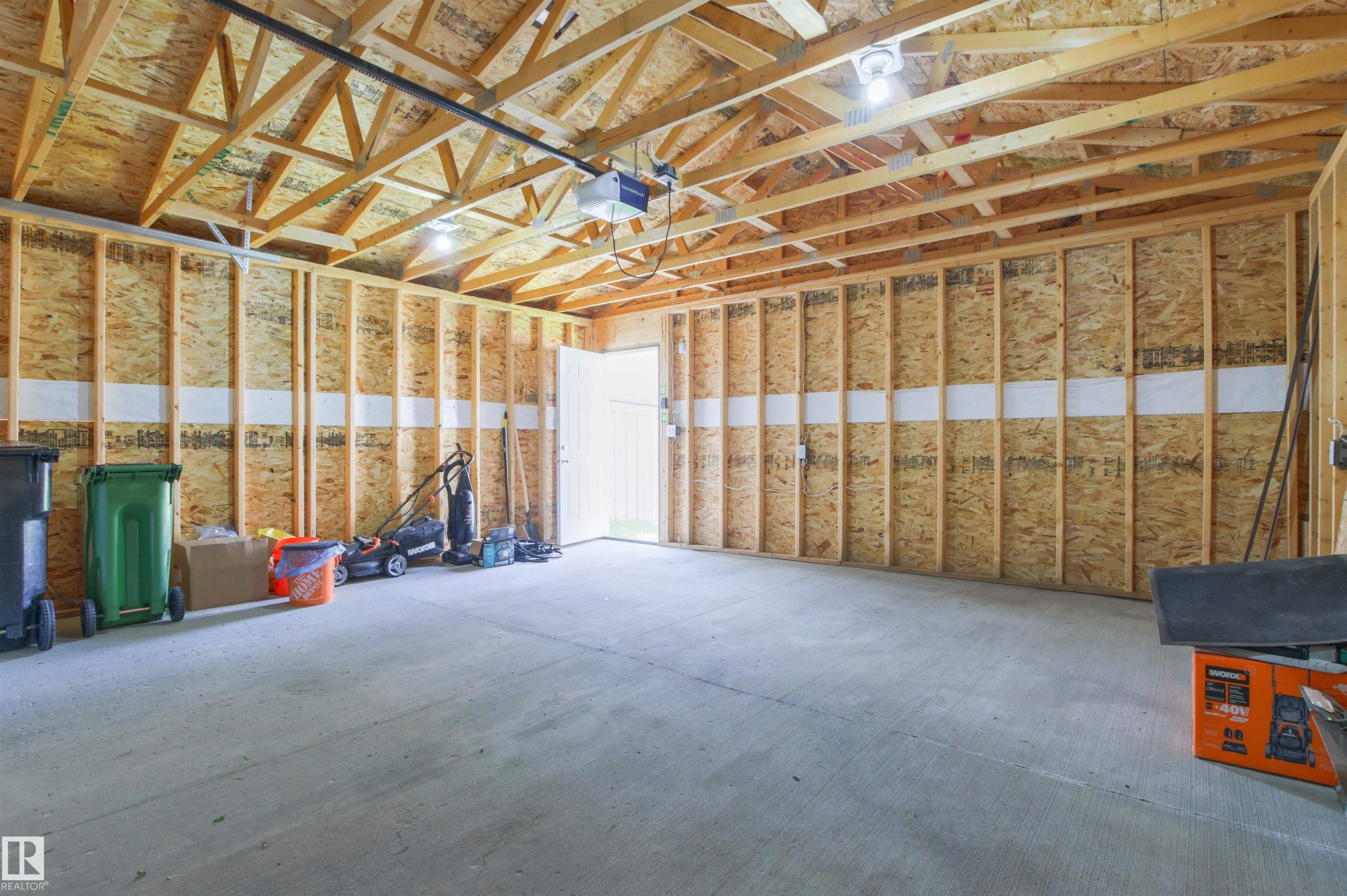 Exposed wood framing with plywood wall sheathing, concrete flooring, and an overhead garage door opener - 9118 Scott Crescent Nw, Edmonton, AB - Indoor Photo Showing Basement