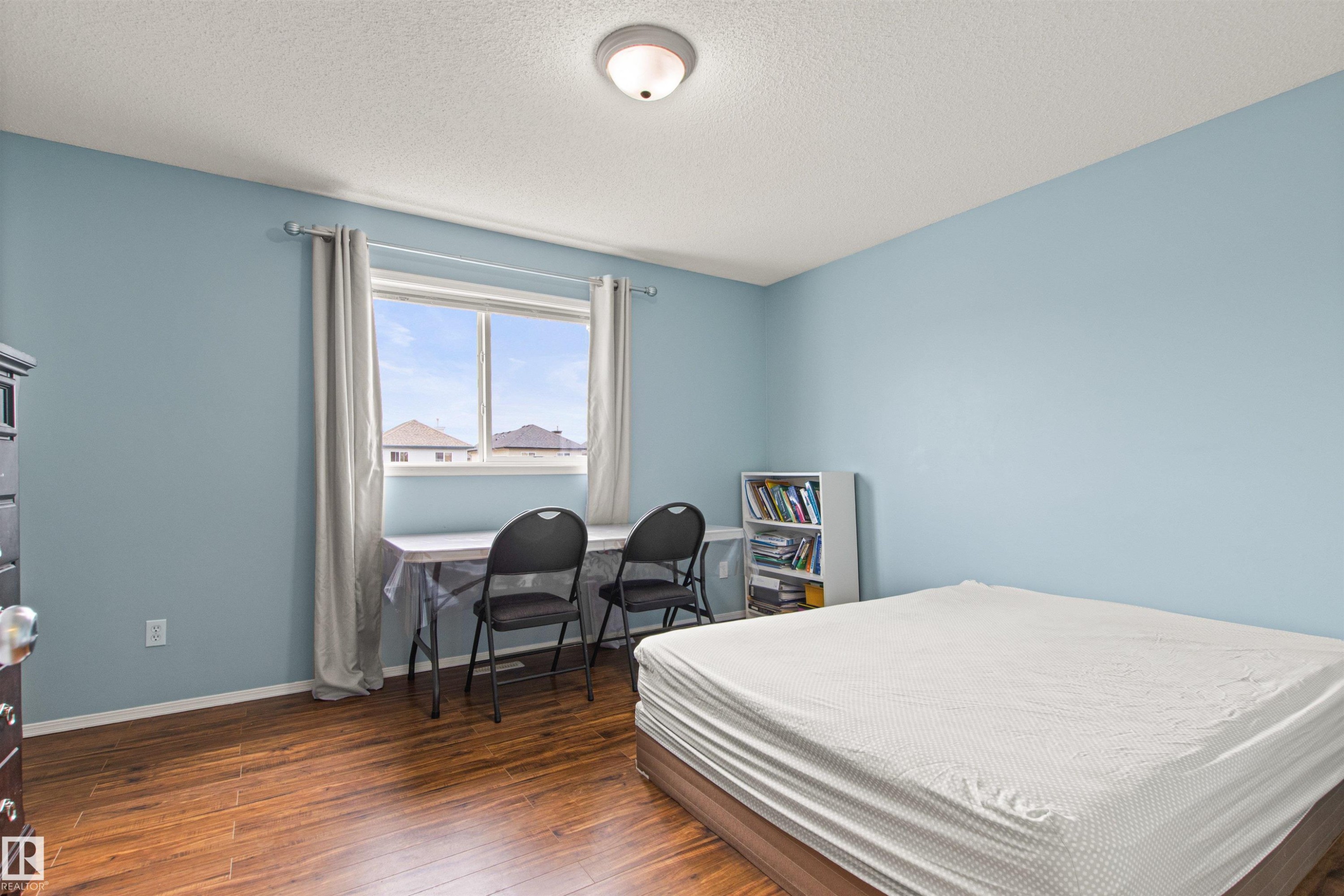 Wood-finish flooring, light blue walls, and a multi-pane window - 9118 Scott Crescent Nw, Edmonton, AB - Indoor Photo Showing Bedroom