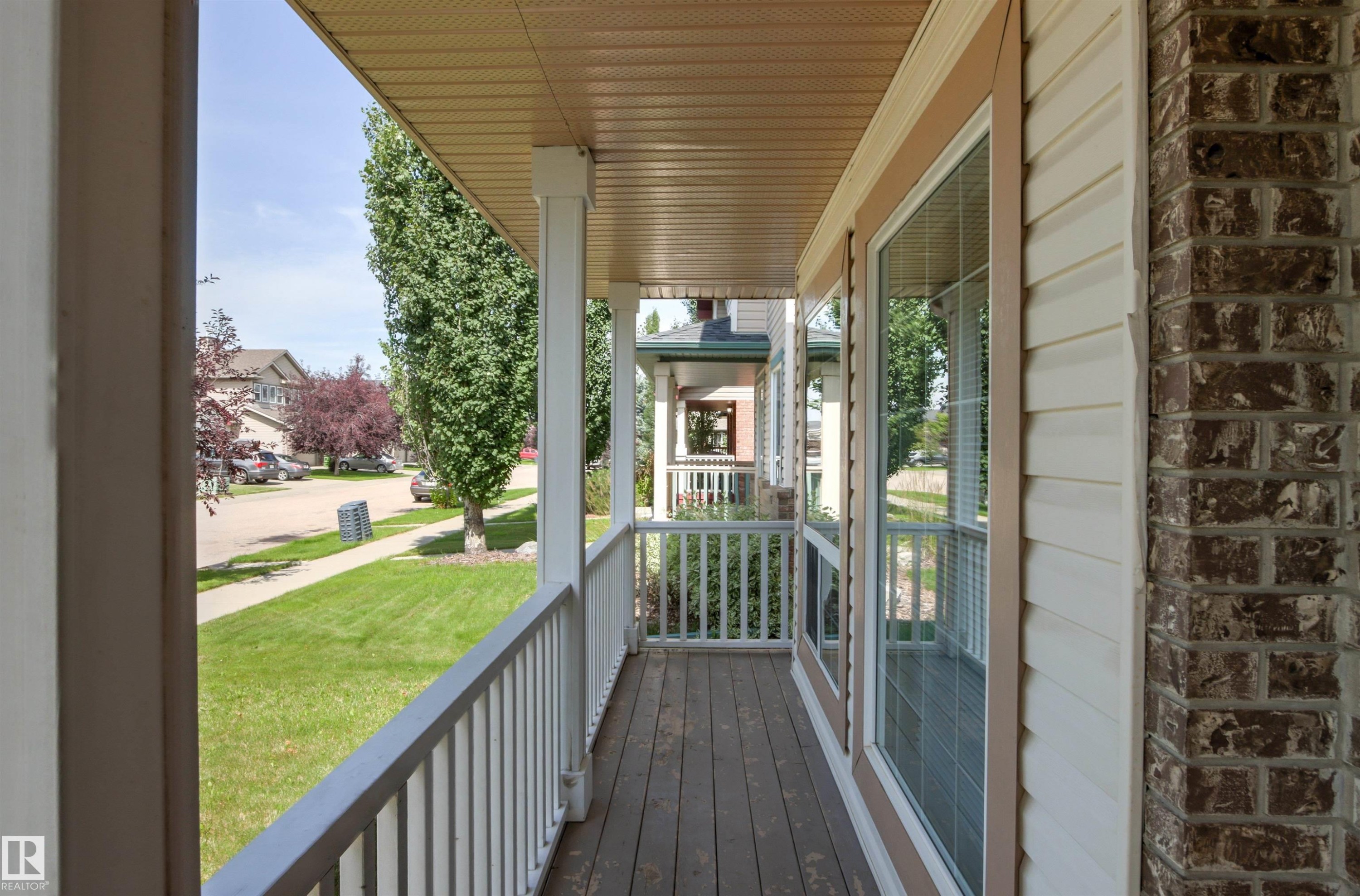 Inviting covered front porch with wood-finish decking, white railings, and substantial support columns - 9118 Scott Crescent Nw, Edmonton, AB - Outdoor With Deck Patio Veranda With Exterior