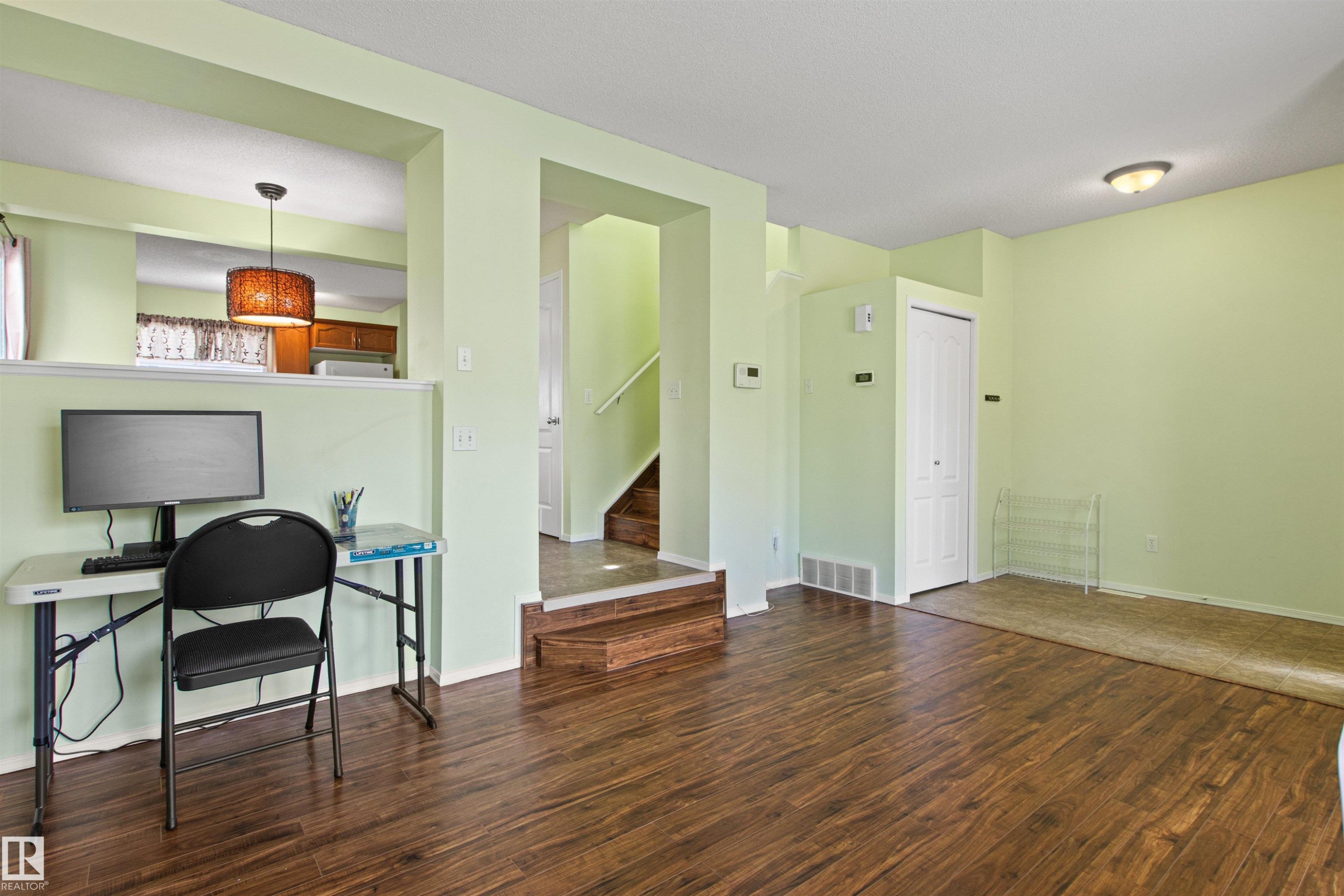 Wood-finish flooring, recessed lighting, half-wall partition, ceiling-mounted light fixture, and interior staircase - 9118 Scott Crescent Nw, Edmonton, AB - Indoor Photo Showing Other Room