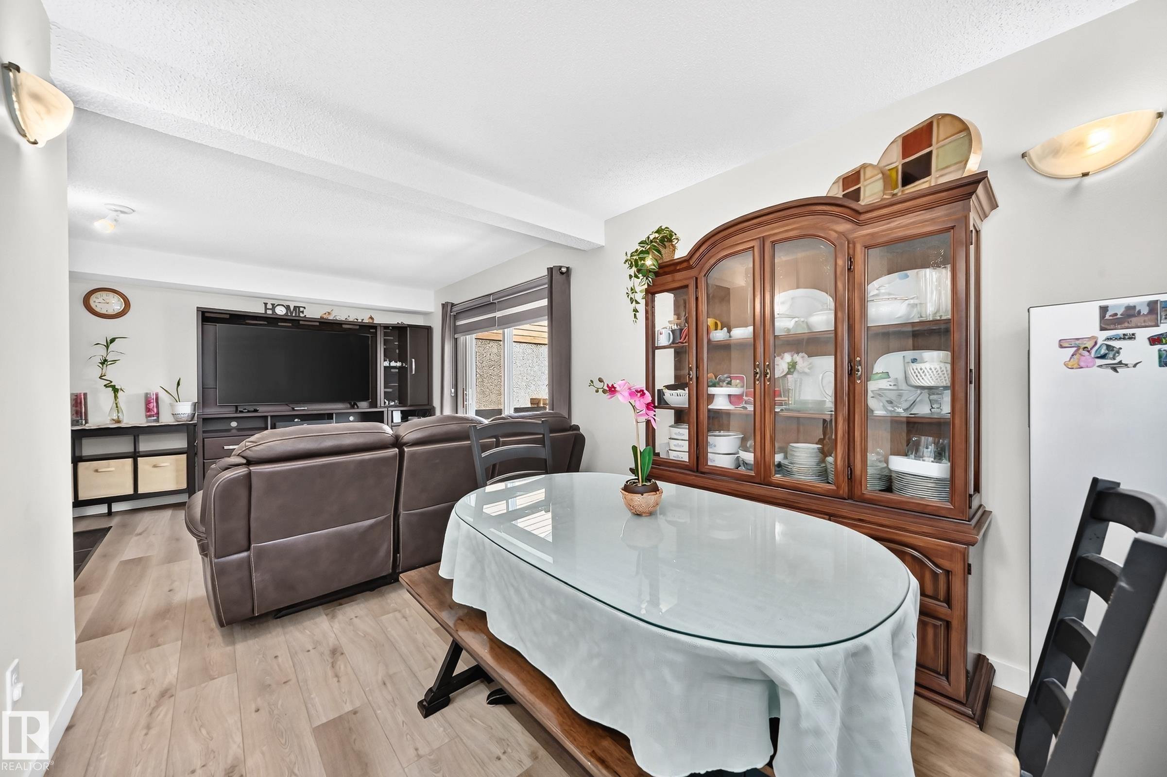 Open-concept living area featuring wood-finish flooring, recessed lighting, and wall-mounted sconces - #22 3812 20 Av Nw, Edmonton, AB - Indoor