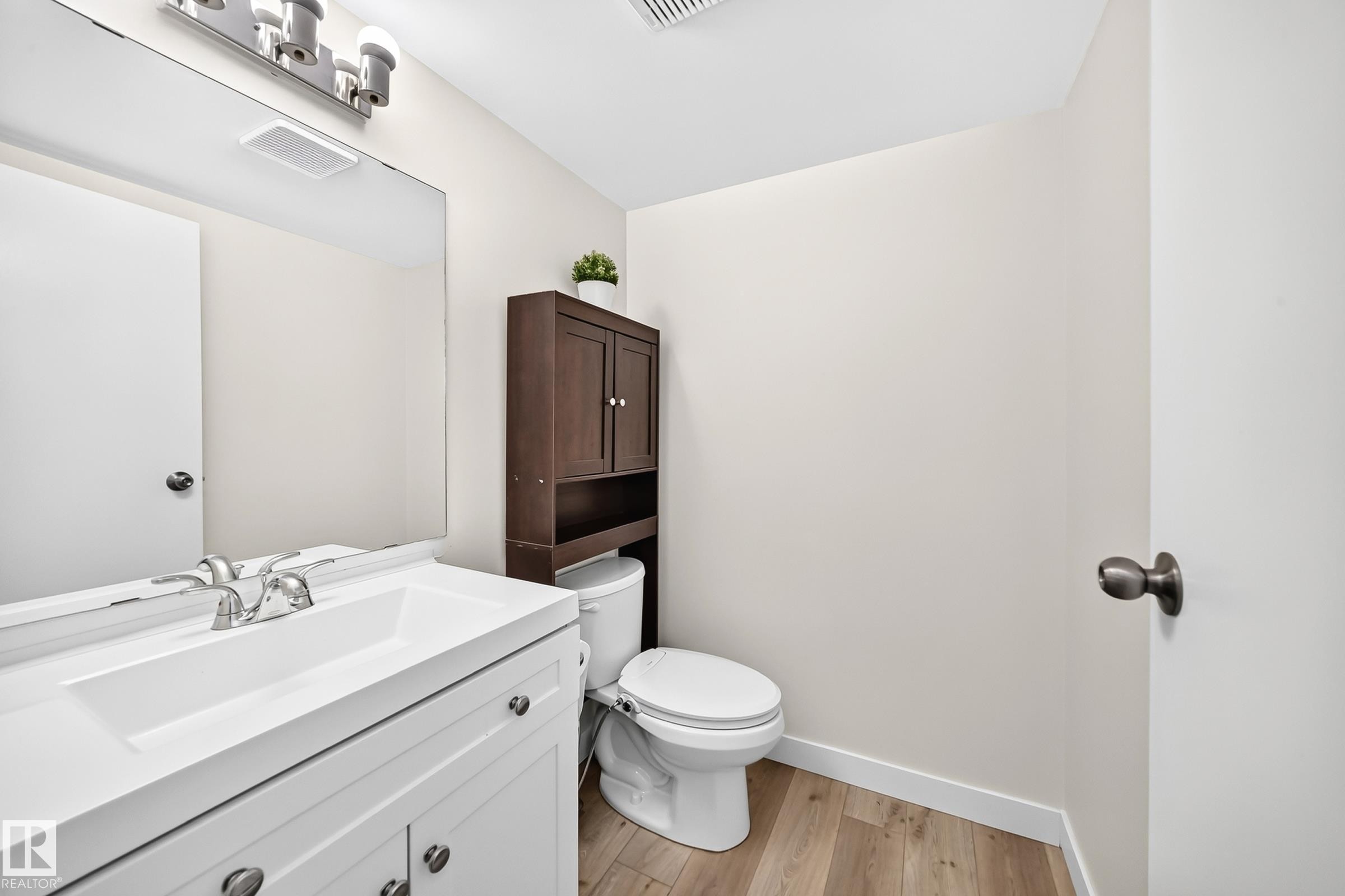White vanity with integrated sink, chrome faucet, and wood-finish flooring - #22 3812 20 Av Nw, Edmonton, AB - Indoor Photo Showing Bathroom