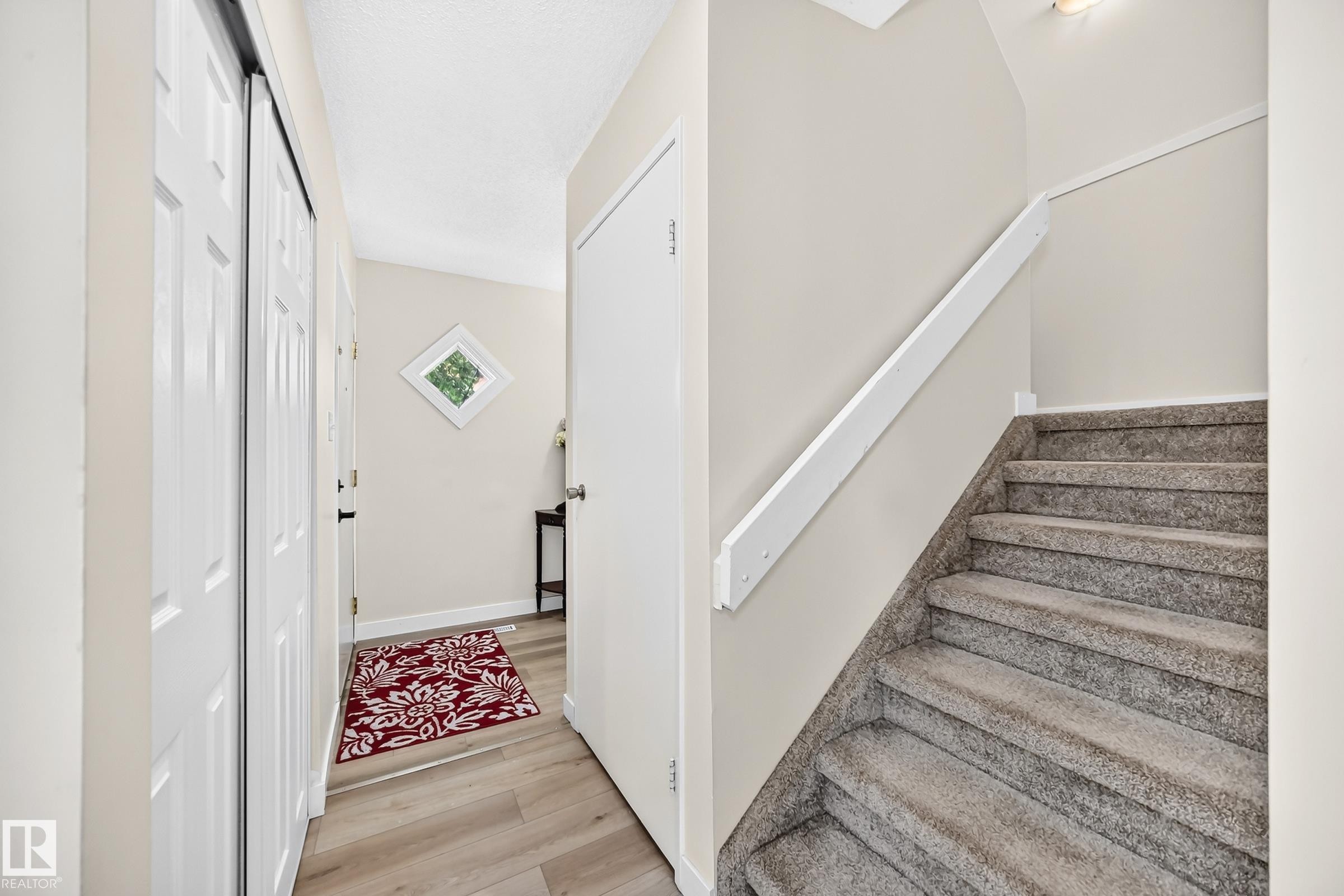 Neutral-toned walls complement wood-finish flooring in the entry - #22 3812 20 Av Nw, Edmonton, AB - Indoor Photo Showing Other Room