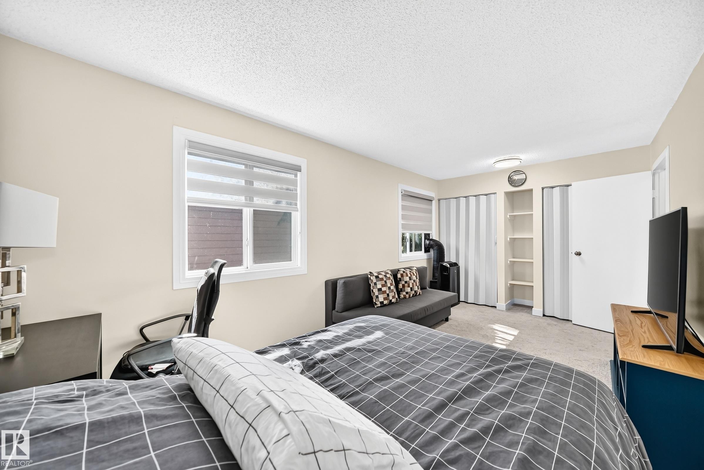 White-framed window with blinds, built-in shelving, white paneled door, and carpeted flooring - #22 3812 20 Av Nw, Edmonton, AB - Indoor Photo Showing Bedroom