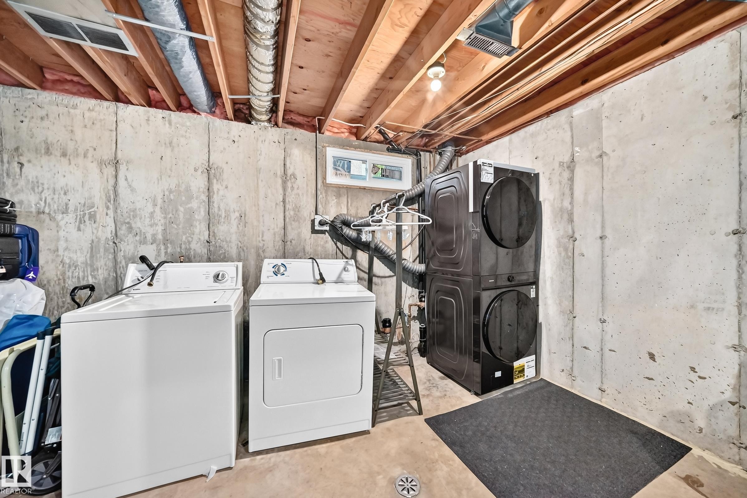 Laundry area with exposed joists, concrete walls, and a drain - #22 3812 20 Av Nw, Edmonton, AB - Indoor Photo Showing Laundry Room