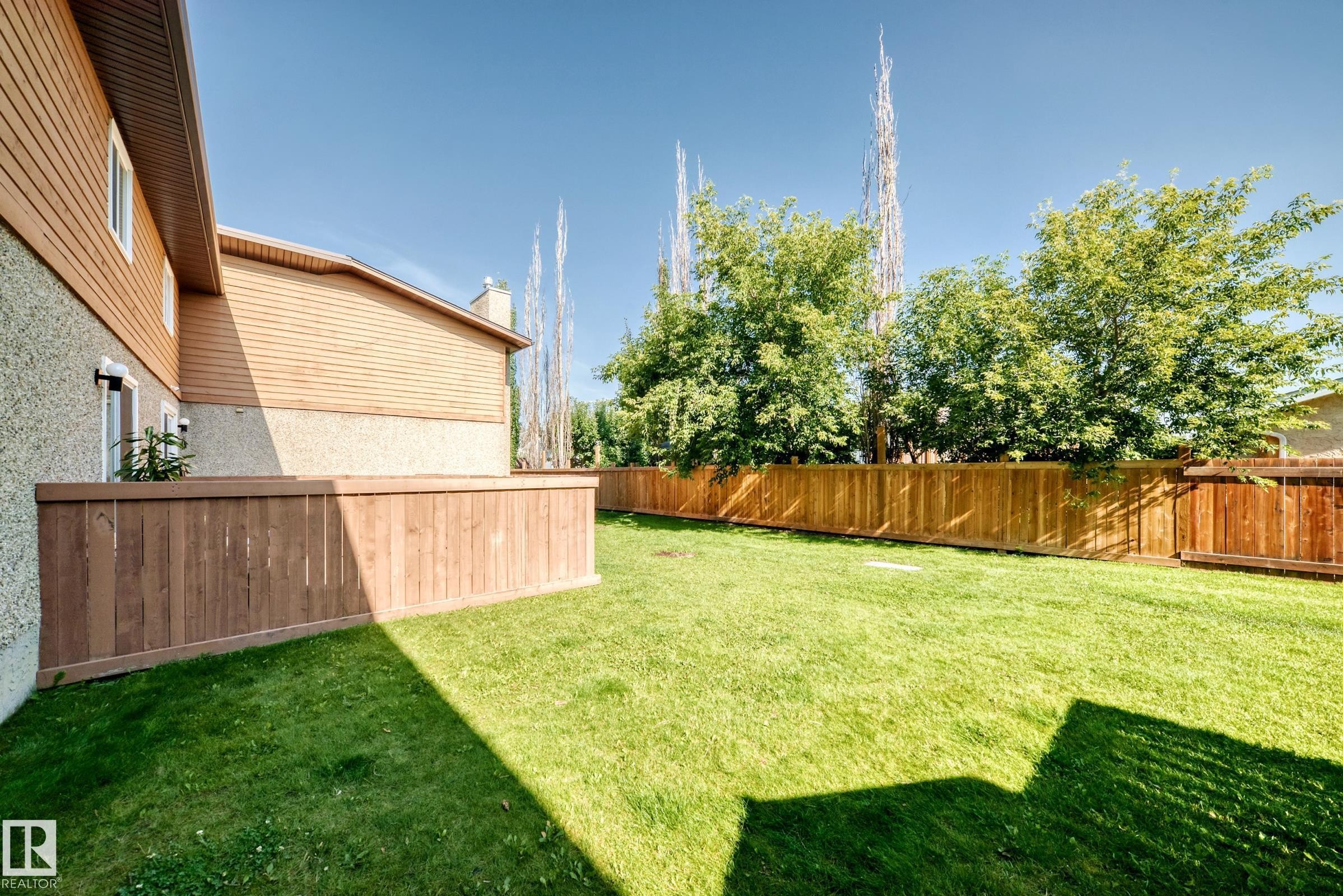 Expansive yard featuring a manicured lawn and perimeter wood fencing - #22 3812 20 Av Nw, Edmonton, AB - Outdoor With Backyard