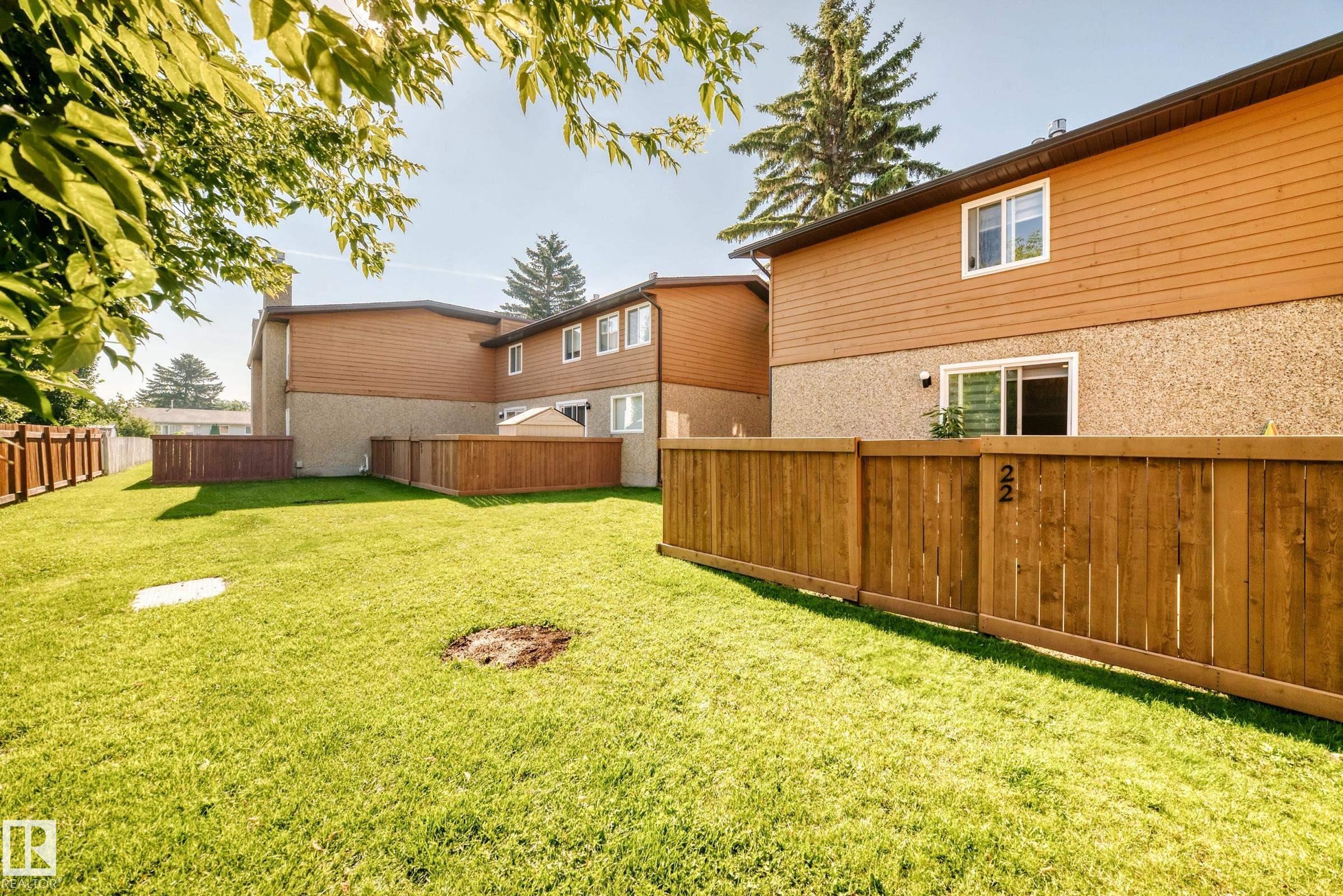 Expansive green lawn with wood privacy fencing - #22 3812 20 Av Nw, Edmonton, AB - Outdoor With Exterior