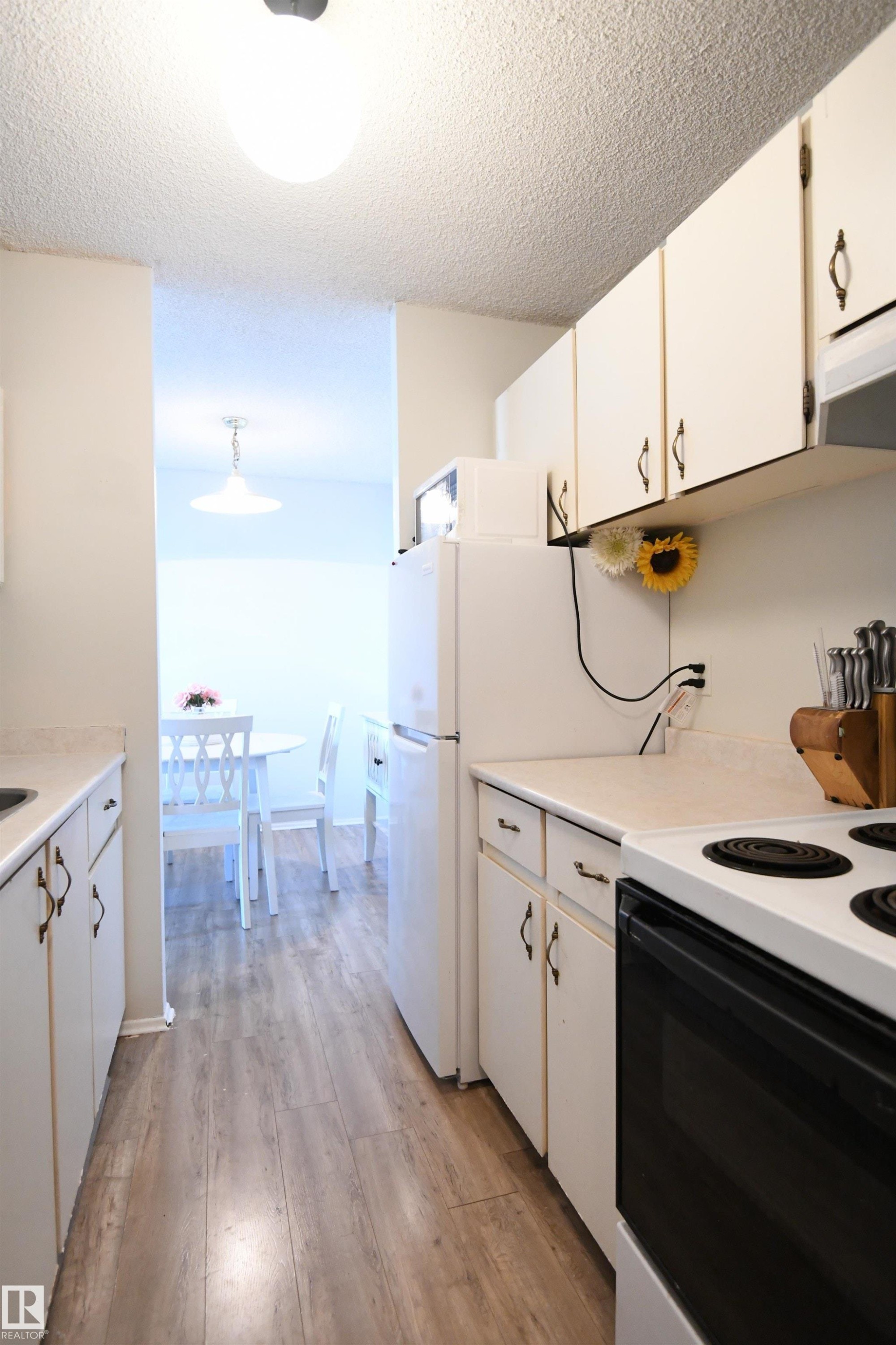 The kitchen is a simple, white, galley design, but is open at both ends, maximizing flow, and keeping the open feel - #1305 13910 Stony Plain Rd Nw, Edmonton, AB - Indoor Photo Showing Kitchen