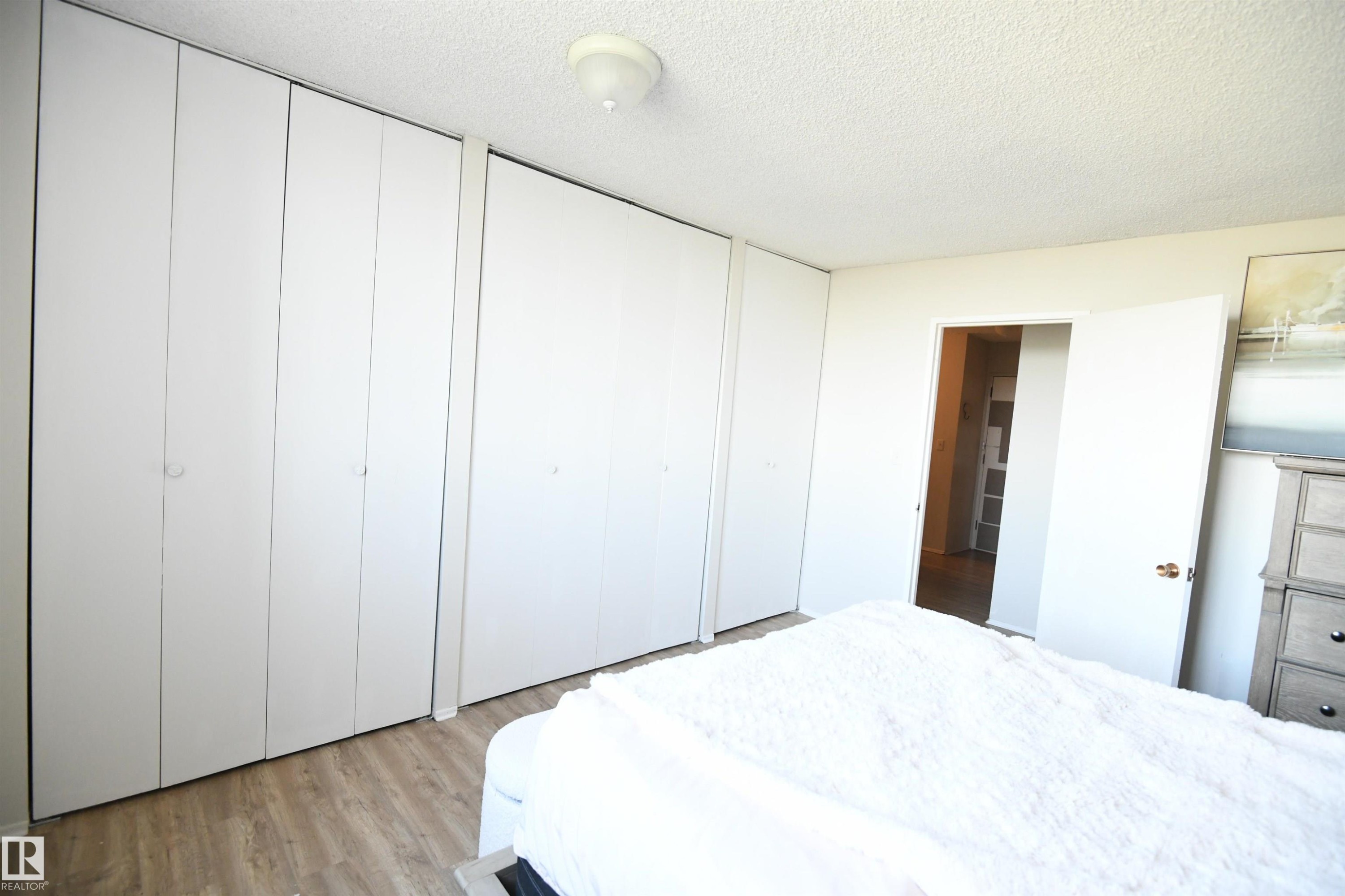 The master bedroom easily supports king sized furniture, has a great window for light and view, as well as a full wall of floor to ceiling closets - #1305 13910 Stony Plain Rd Nw, Edmonton, AB - Indoor Photo Showing Bedroom