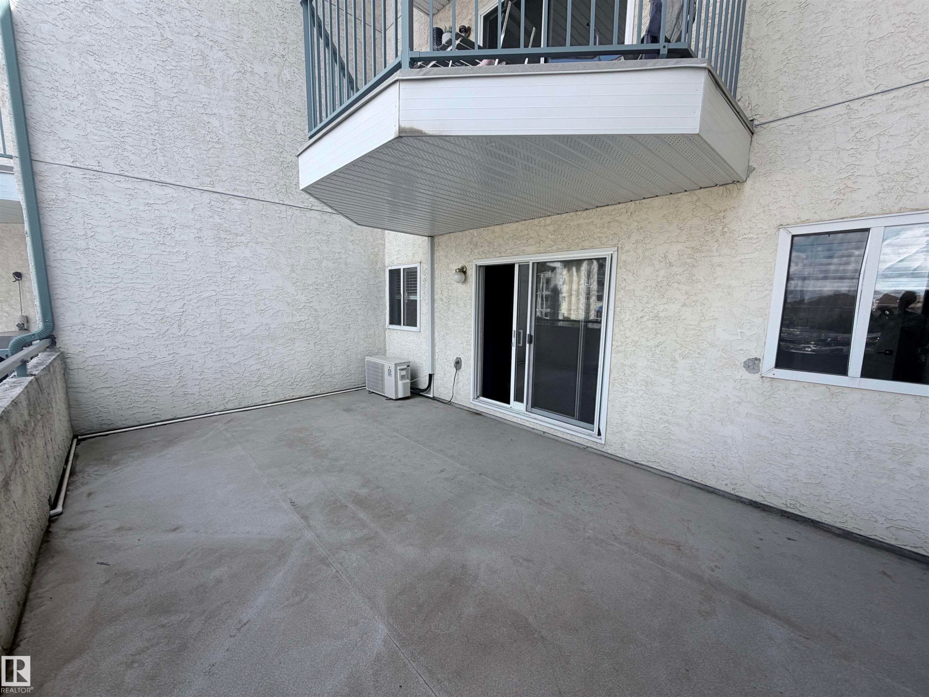 Concrete patio with textured stucco exterior - #208 6710 158 Av Nw, Edmonton, AB - Outdoor With Balcony With Exterior