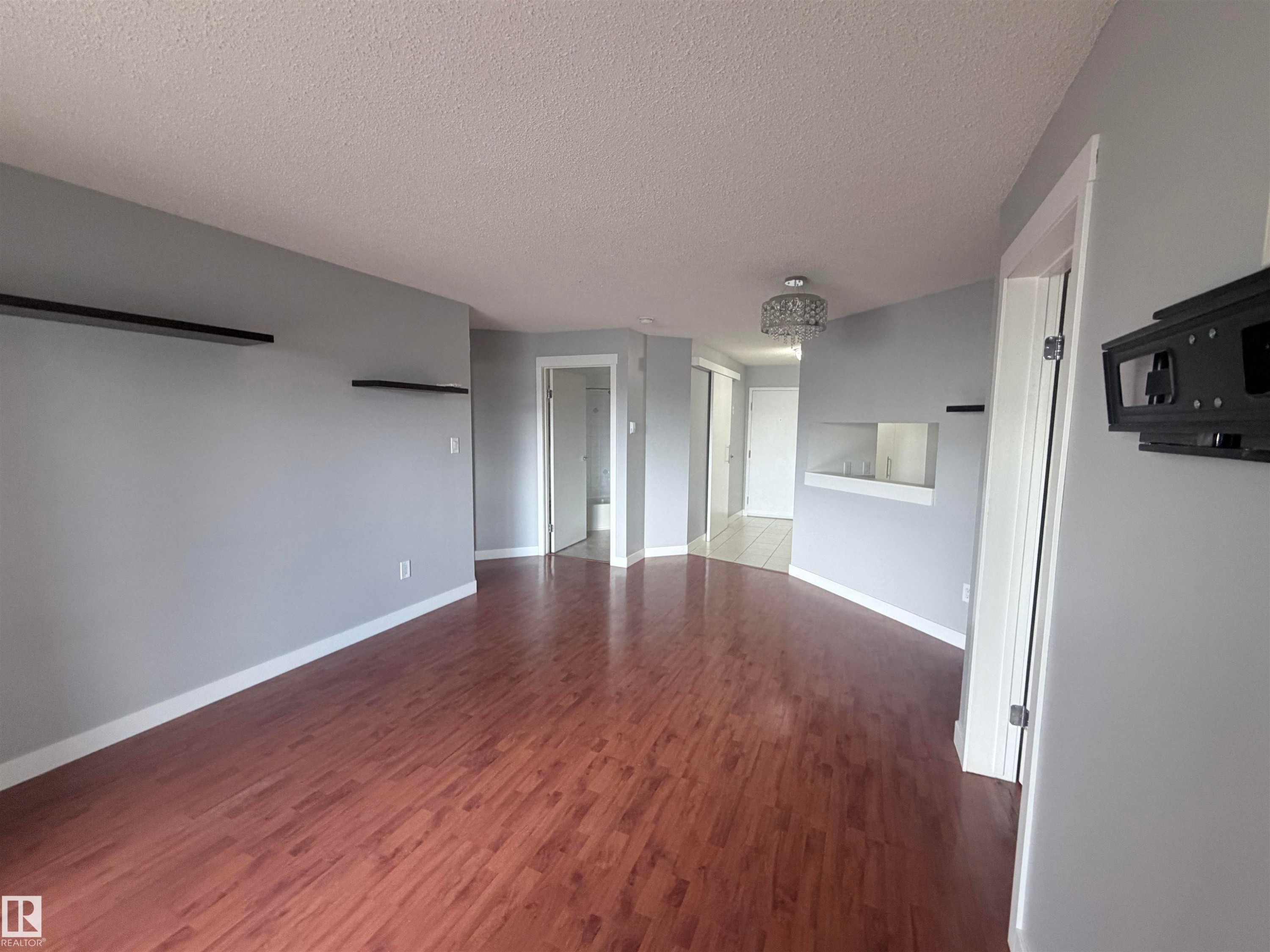 Spacious interior featuring wood-finish flooring and light gray painted walls - #208 6710 158 Av Nw, Edmonton, AB - Indoor Photo Showing Other Room