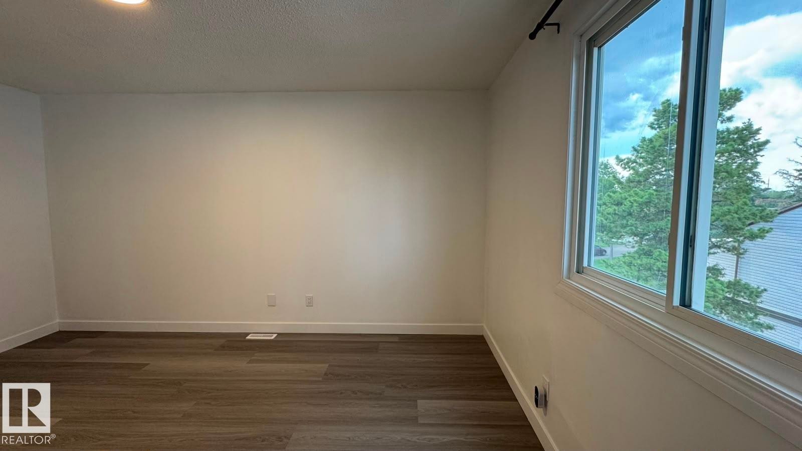 Wood-finish flooring, white painted walls, and a large window with white trim - 41 Lancaster Terrace Nw, Edmonton, AB - Indoor Photo Showing Other Room