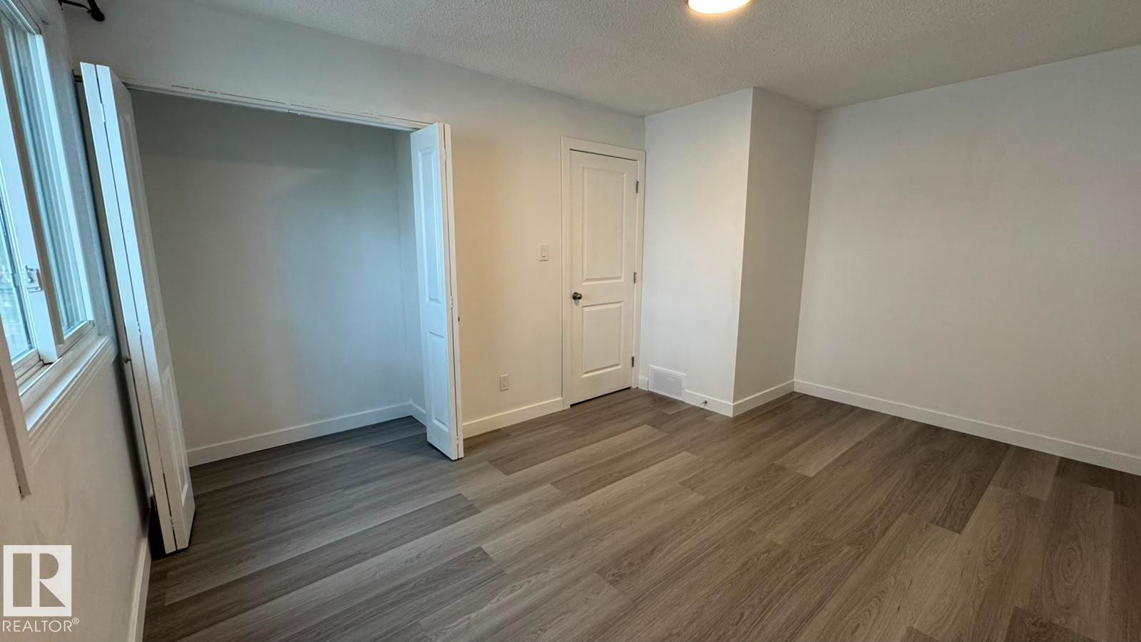 Wood-finish flooring, white walls, built-in closet, and a white interior door - 41 Lancaster Terrace Nw, Edmonton, AB - Indoor Photo Showing Other Room