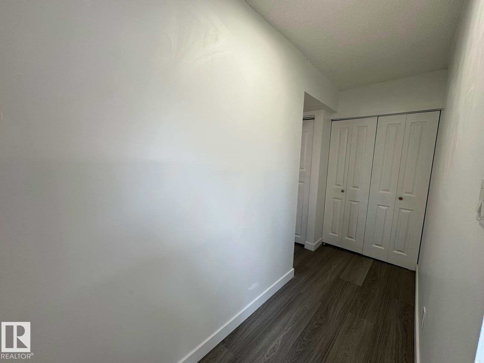 Wood-finish flooring, white walls, and bi-fold closet doors - 41 Lancaster Terrace Nw, Edmonton, AB - Indoor Photo Showing Other Room