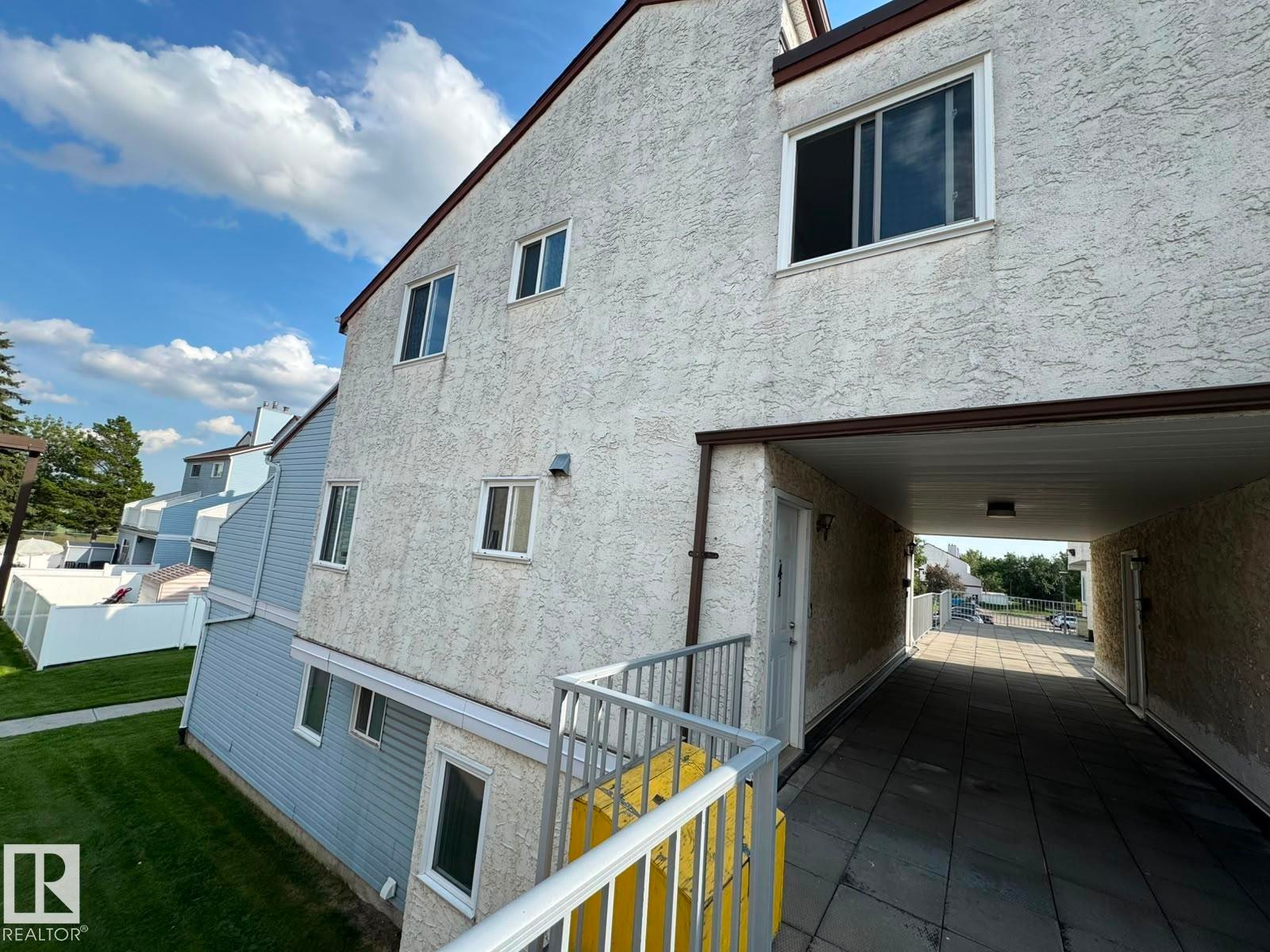 Stucco exterior with multiple windows, leading to an exterior covered walkway - 41 Lancaster Terrace Nw, Edmonton, AB - Outdoor With Exterior
