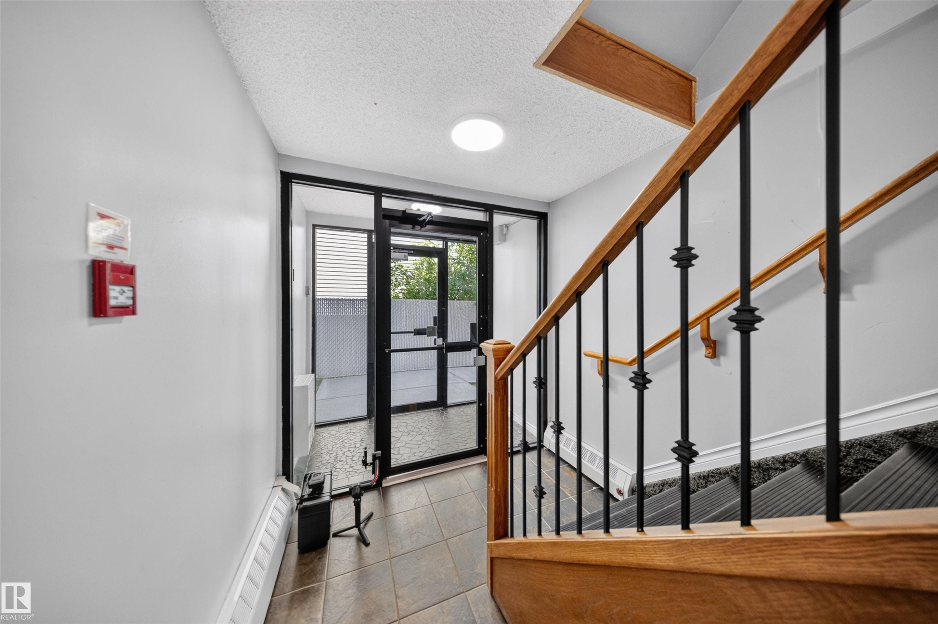 Modern entryway featuring a tile-finish floor, recessed ceiling lighting, and a striking staircase with wooden handrails and black metal balusters - #4 4616 47 St, Leduc, AB - Indoor Photo Showing Other Room