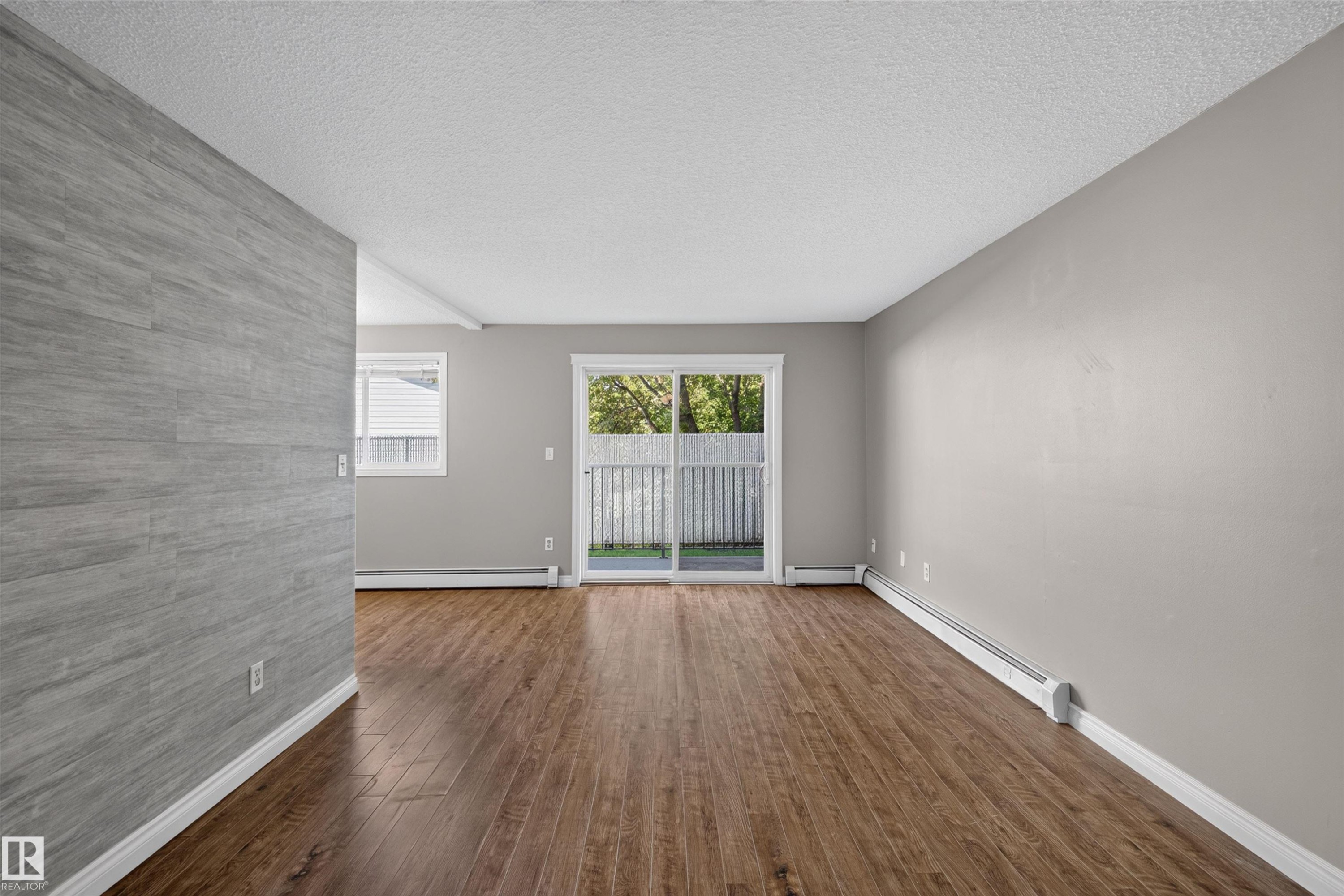 Wood-finish flooring throughout, light gray wall finishes, and a gray wood-finish accent wall - #4 4616 47 St, Leduc, AB - Indoor Photo Showing Other Room