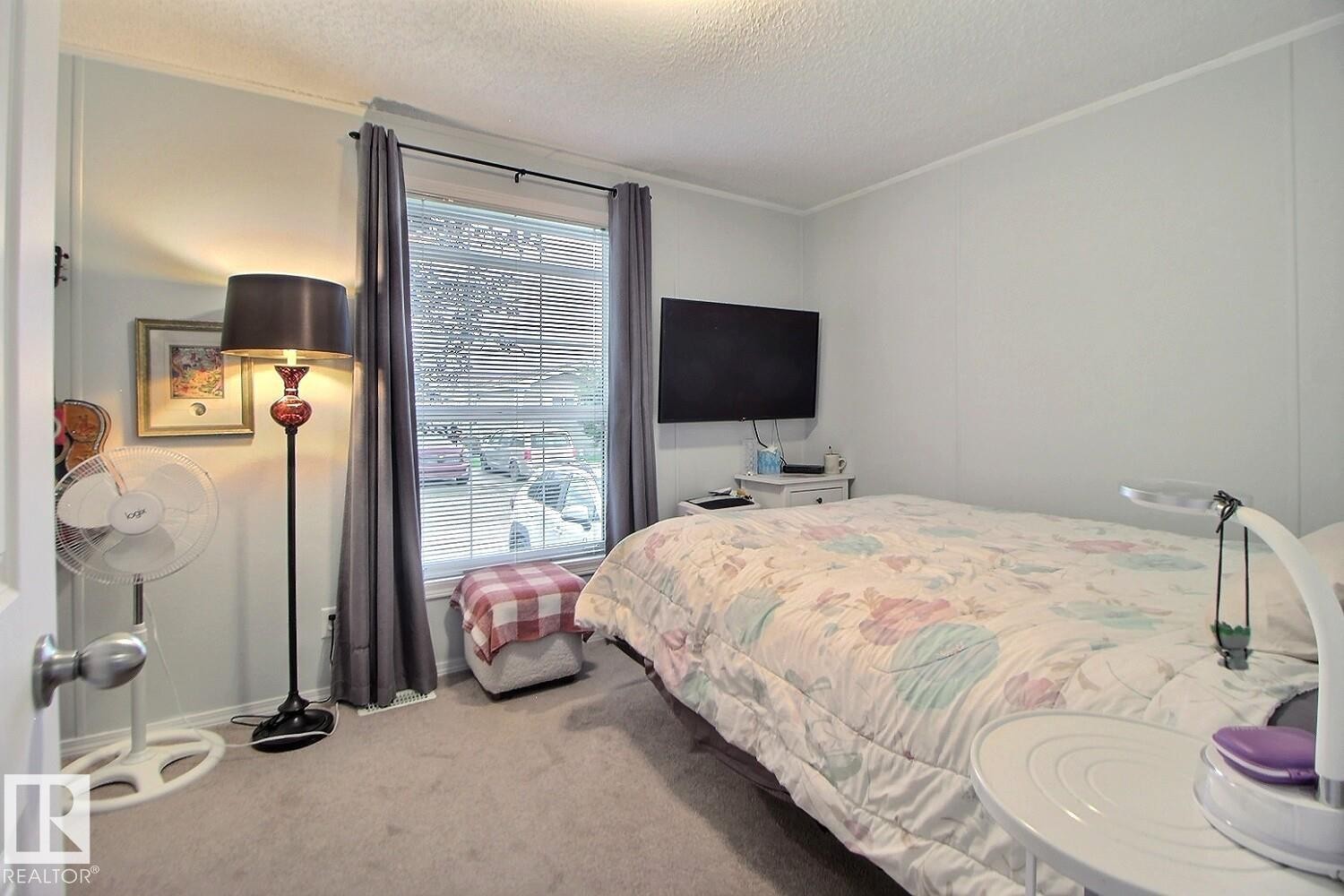 Wall-mounted television, window with blinds and drapes, and carpeting - 417 Oak Wood Crescent Northwest, Edmonton, AB - Indoor Photo Showing Bedroom