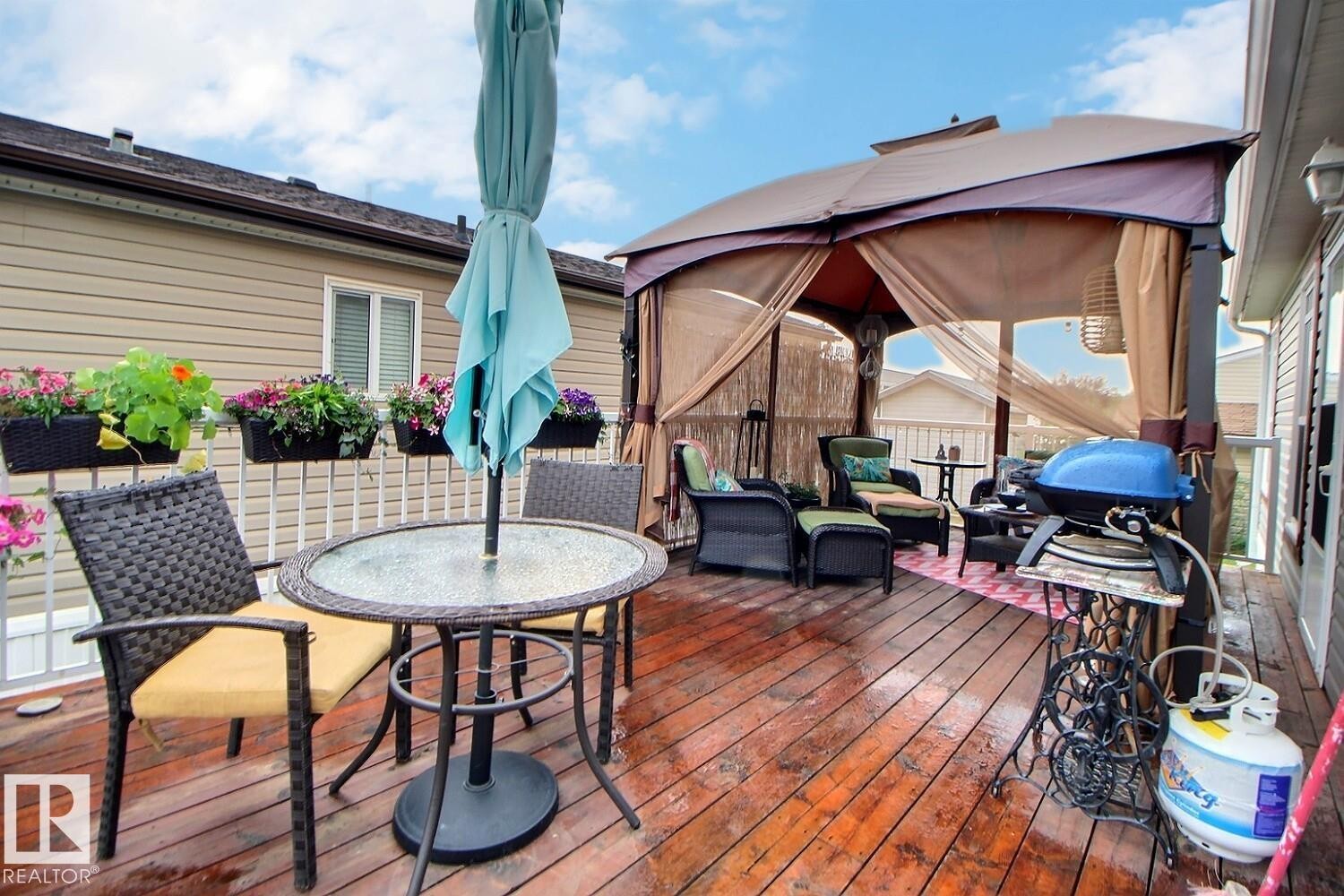 Expansive wood deck with a built-in gazebo featuring privacy screens, a glass-top table, and a white railing with attached planters - 417 Oak Wood Crescent Northwest, Edmonton, AB - Outdoor With Deck Patio Veranda With Exterior