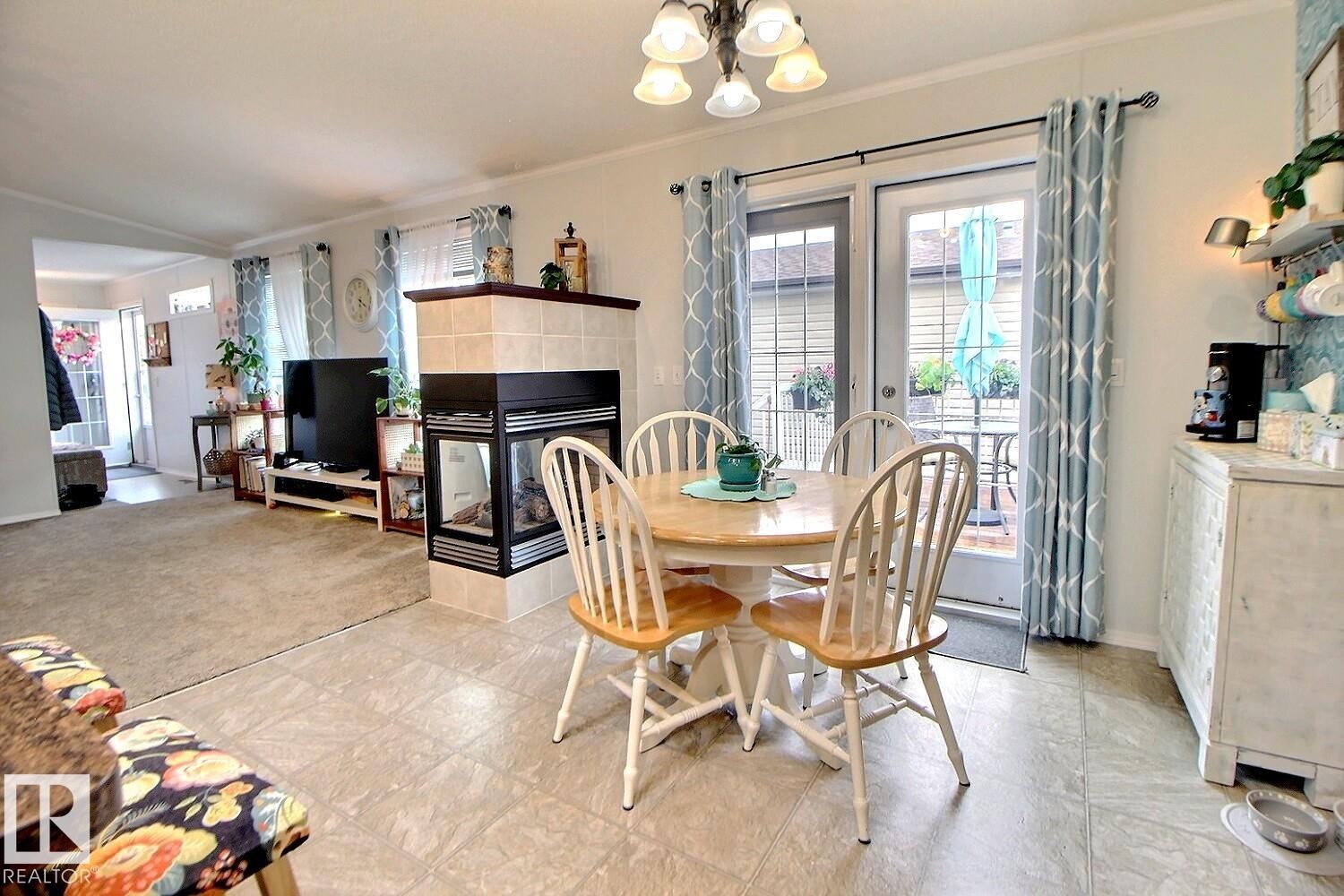 Tile flooring, tiled fireplace with dark trim, recessed lighting, and patio access - 417 Oak Wood Crescent Northwest, Edmonton, AB - Indoor Photo Showing Dining Room With Fireplace
