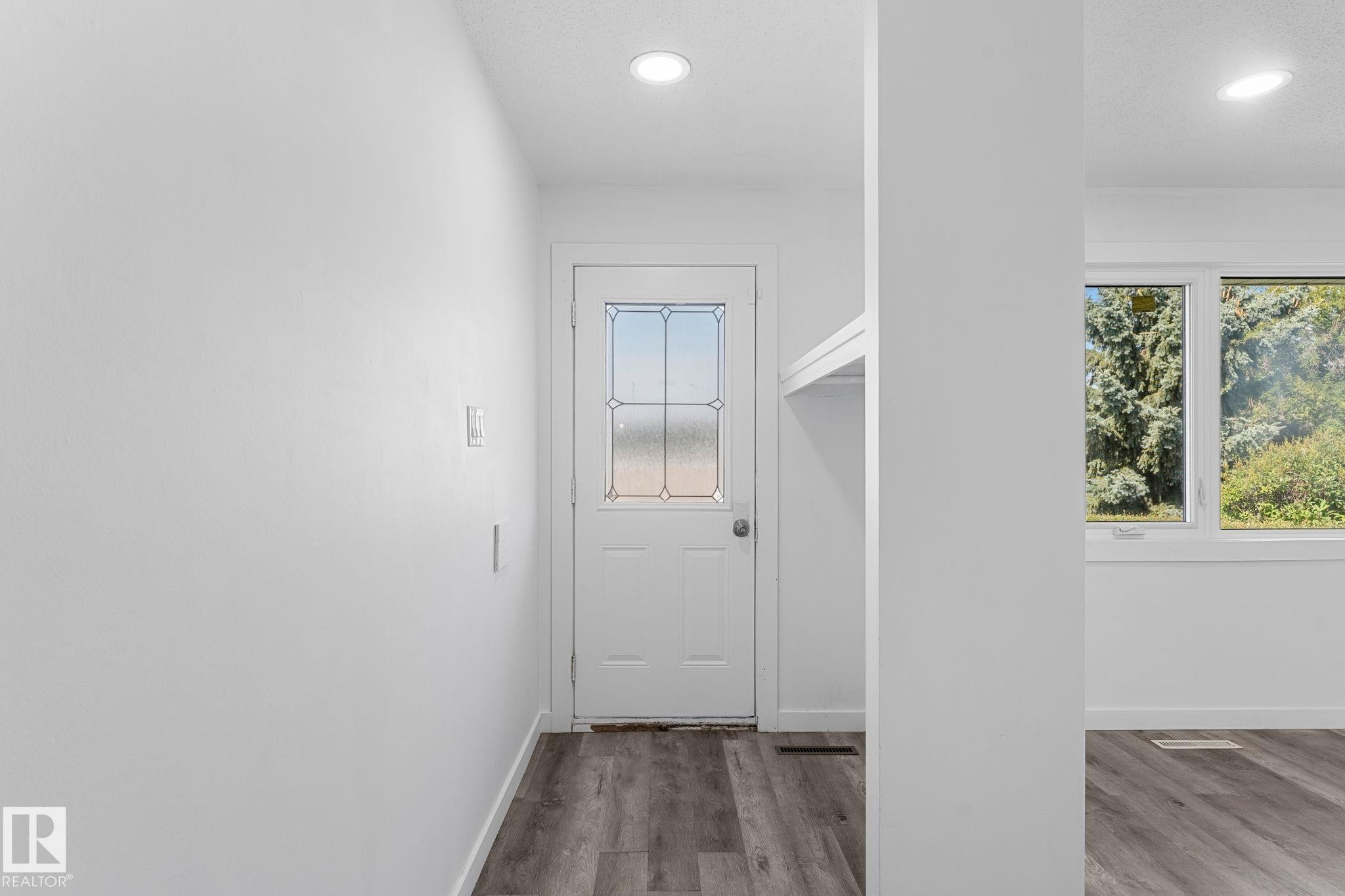 White interior door with decorative glass inserts, recessed lighting, wood-finish flooring, and white trim - 7823 136 Avenue Nw, Edmonton, AB - Indoor Photo Showing Other Room