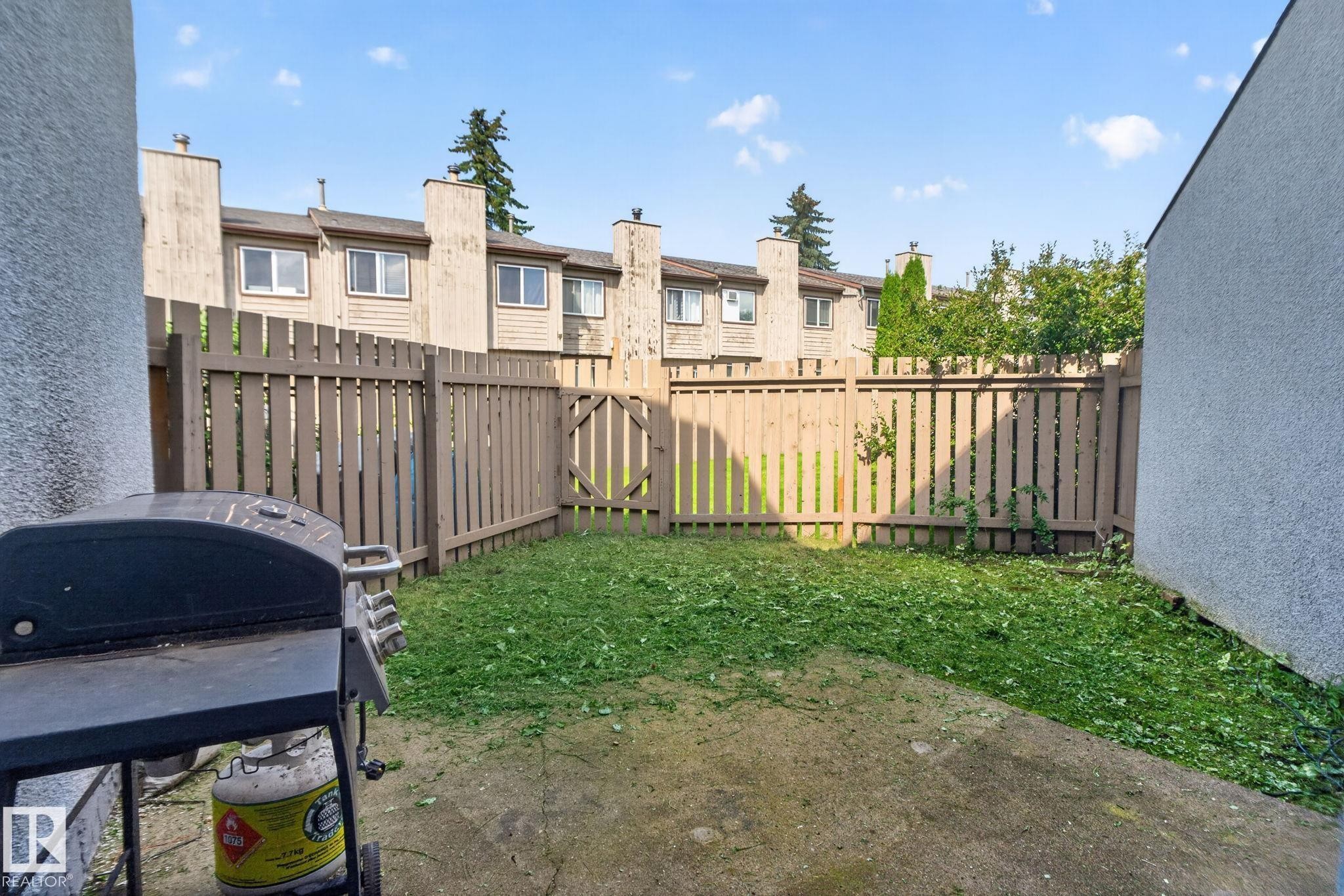 Enclosed backyard featuring a privacy fence with a gate, concrete patio, and garden area - 17775 95 Street Nw, Edmonton, AB - Outdoor