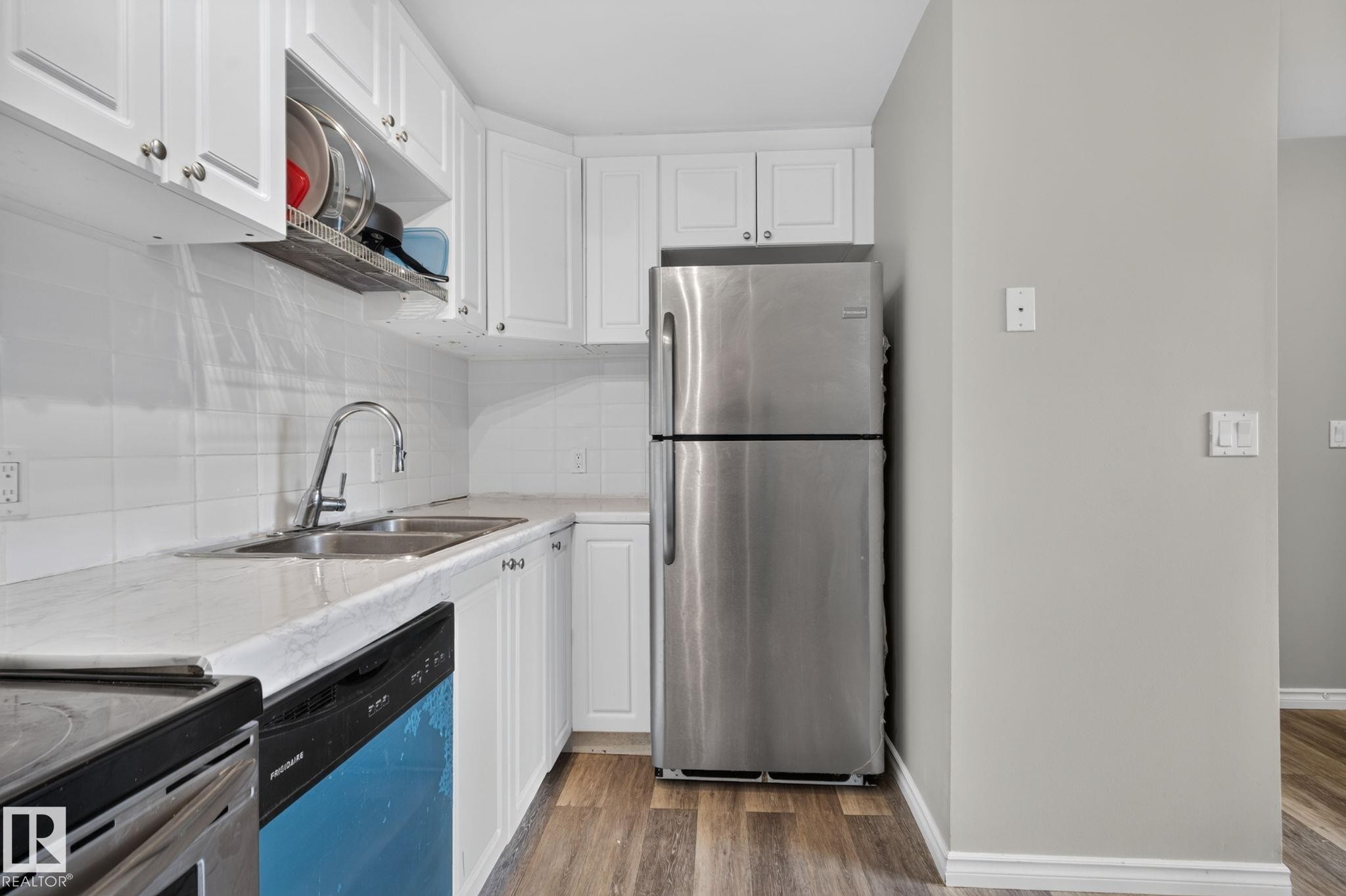 White cabinetry, white subway tile backsplash, stainless steel appliances, dual basin sink, and wood-finish flooring - 17775 95 Street Nw, Edmonton, AB - Indoor Photo Showing Kitchen With Double Sink With Upgraded Kitchen