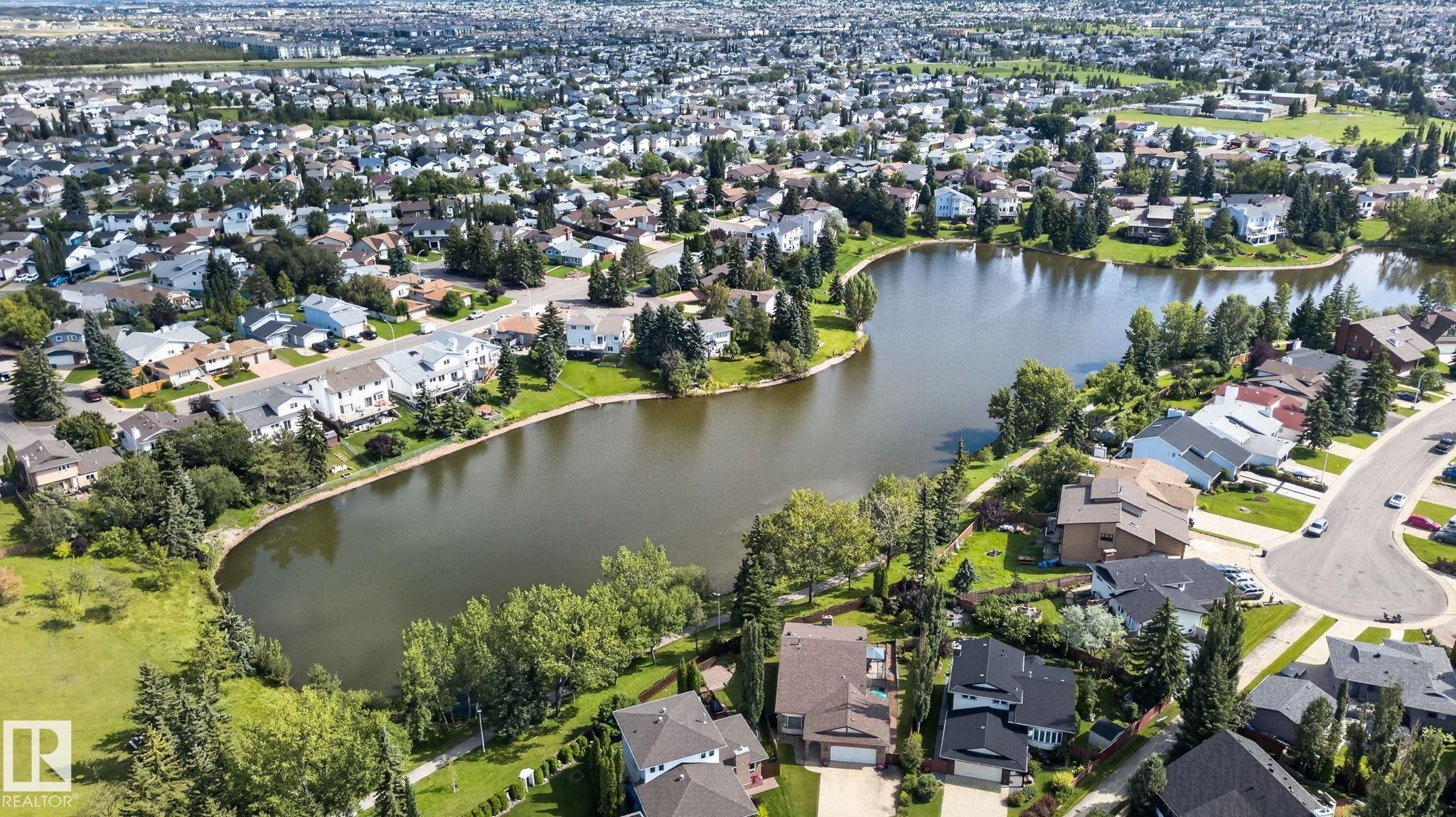 Expansive residential area featuring a central body of water surrounded by mature trees - 17775 95 Street Nw, Edmonton, AB - Outdoor With Body Of Water With View