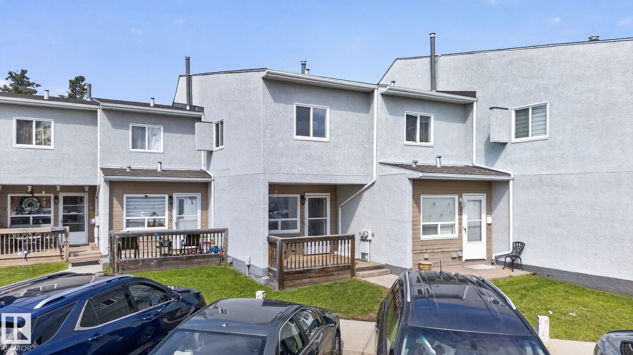 Light-colored stucco exterior with contrasting trim, featuring multiple windows and a wooden deck - 17775 95 Street Nw, Edmonton, AB - Outdoor With Deck Patio Veranda