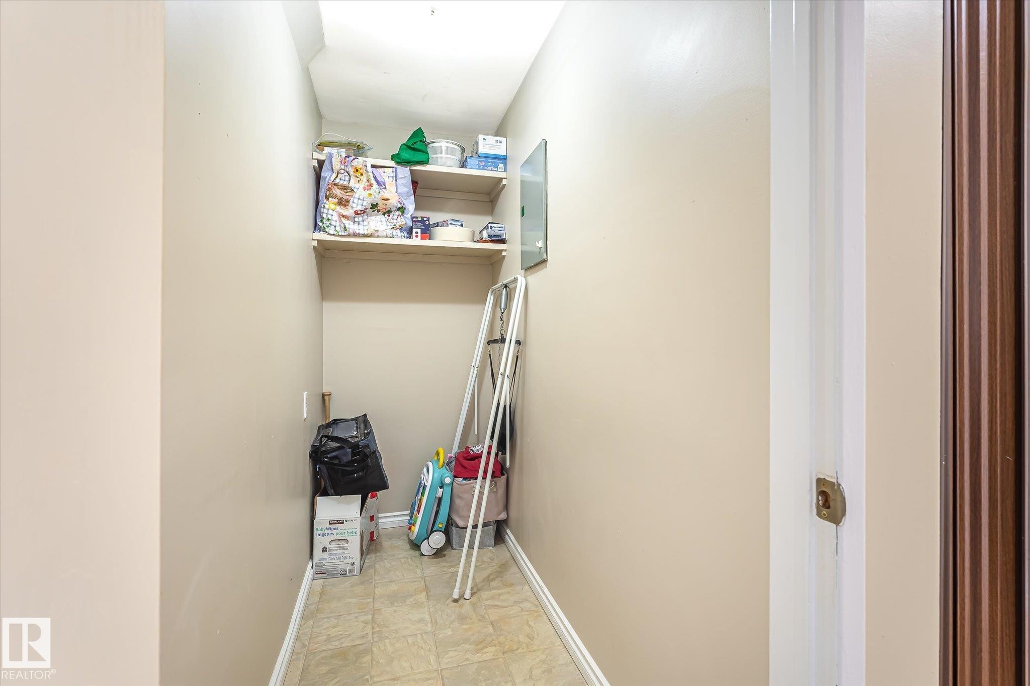 Recessed storage area featuring two built-in shelves and tile flooring - 6471 180 Street Nw, Edmonton, AB - Indoor