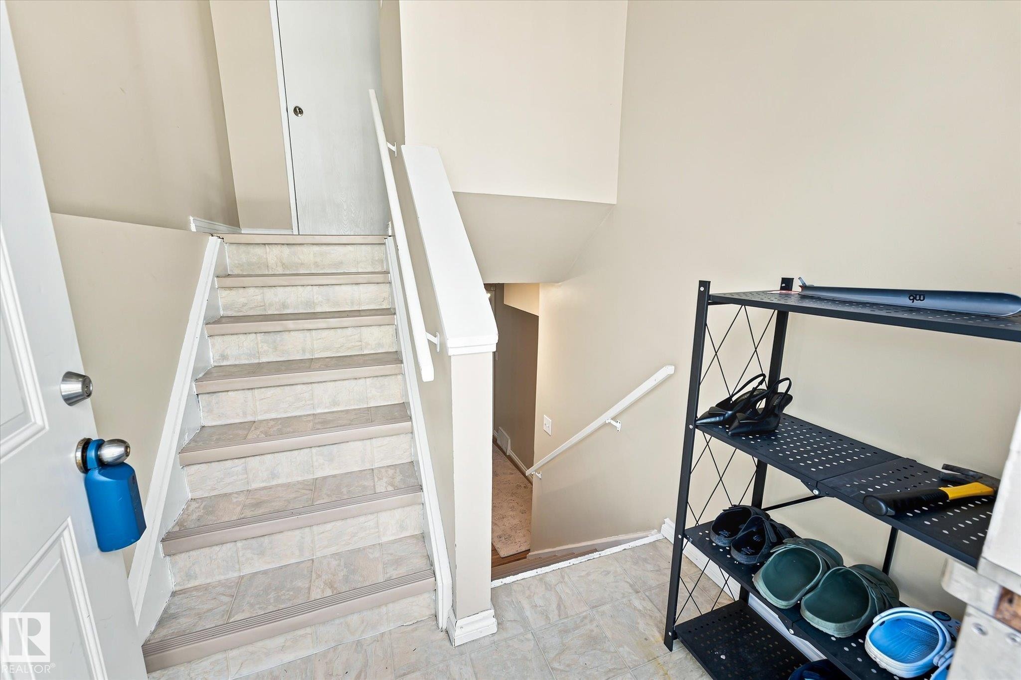 Staircase with tile-finish treads and risers, white painted handrails, and neutral wall tones - 6471 180 Street Nw, Edmonton, AB - Indoor Photo Showing Other Room
