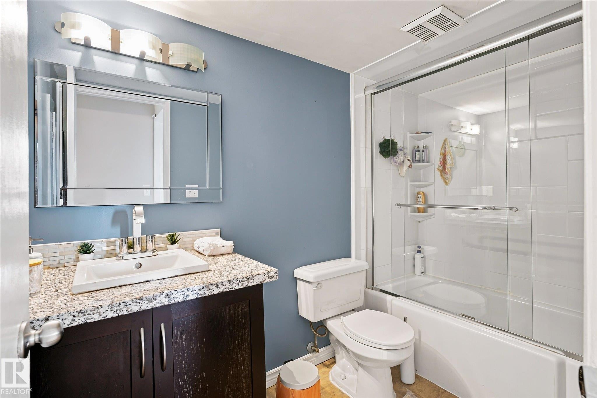 Vanity with a granite-style countertop, undermount sink, and dark wood-finish cabinetry - 6471 180 Street Nw, Edmonton, AB - Indoor Photo Showing Bathroom
