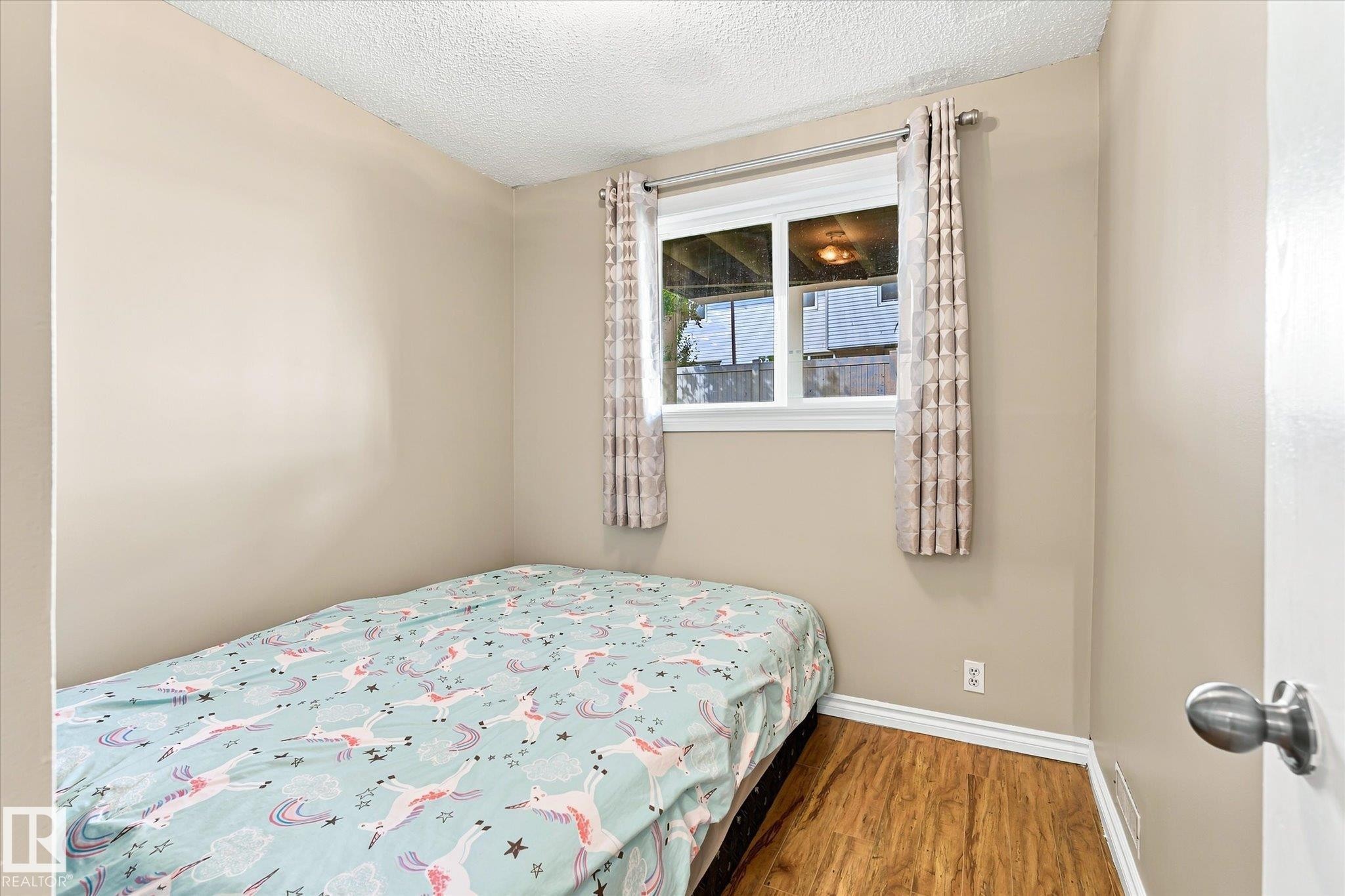 Wood-finish flooring with white trim, a single window, and light-toned wall paint - 6471 180 Street Nw, Edmonton, AB - Indoor Photo Showing Bedroom