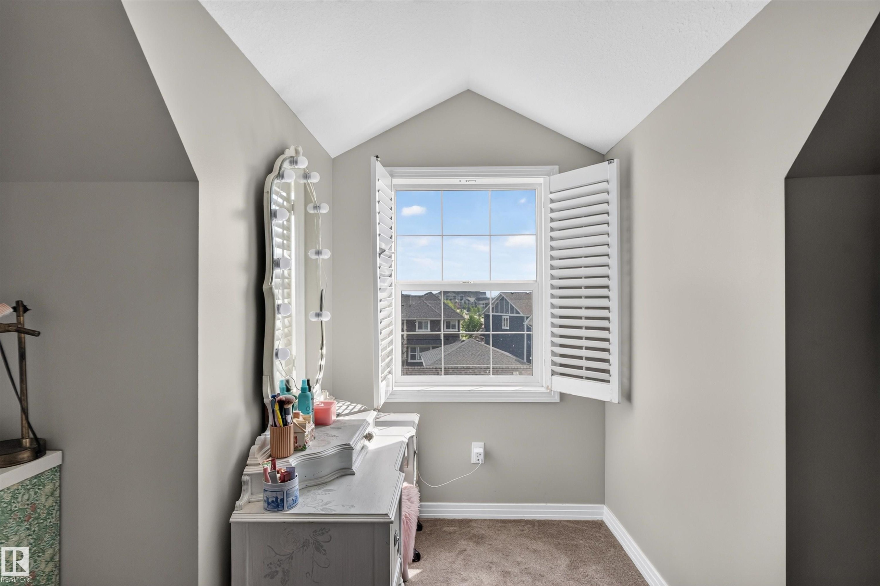 Attic space with sloped walls, a single window with white plantation shutters, and light gray wall paint - 4471 Mccrae Avenue Nw, Edmonton, AB
