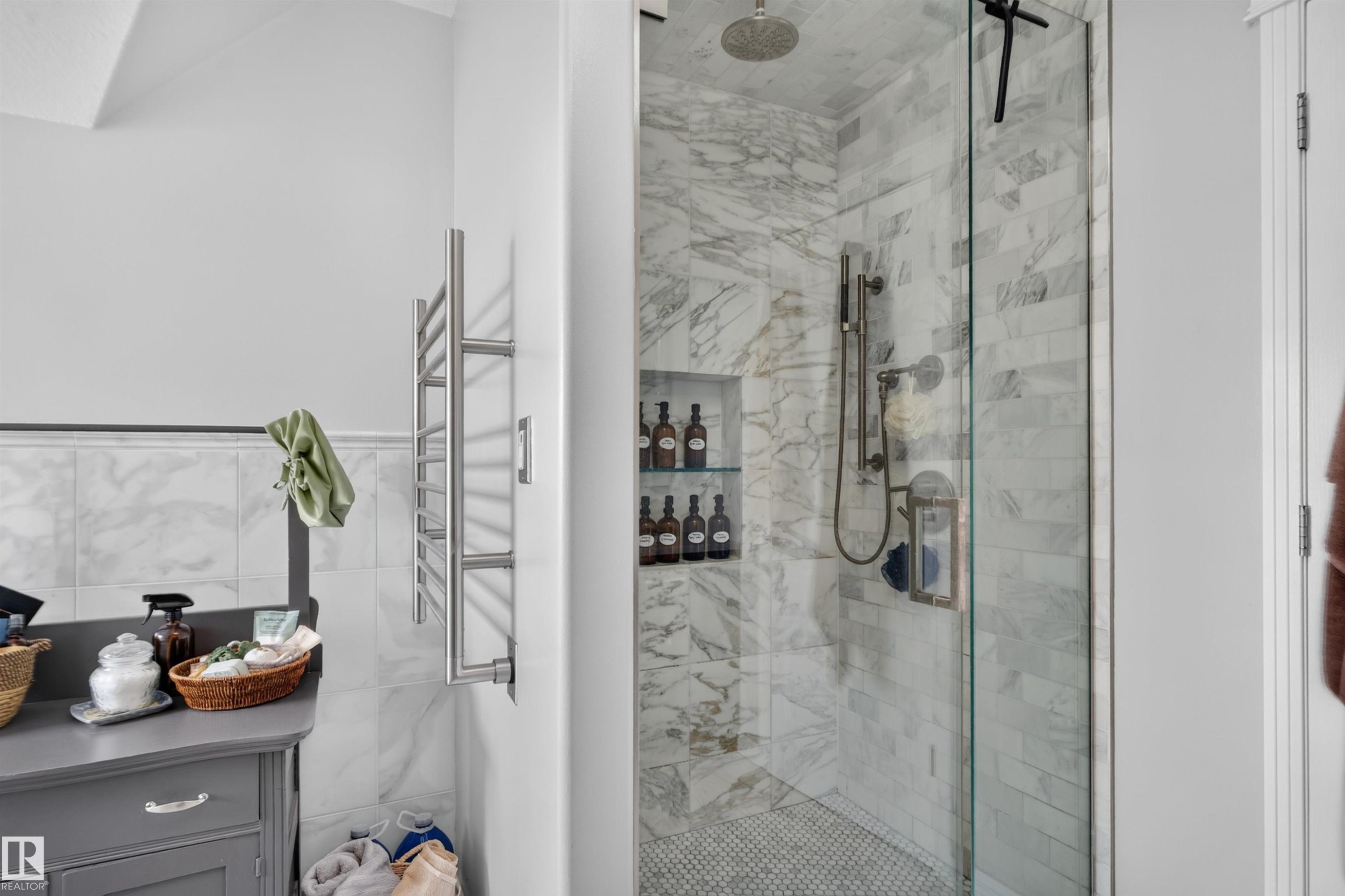 Glass-enclosed shower with marble-style tile walls, rain shower head, and built-in shelving - 4471 Mccrae Avenue Nw, Edmonton, AB