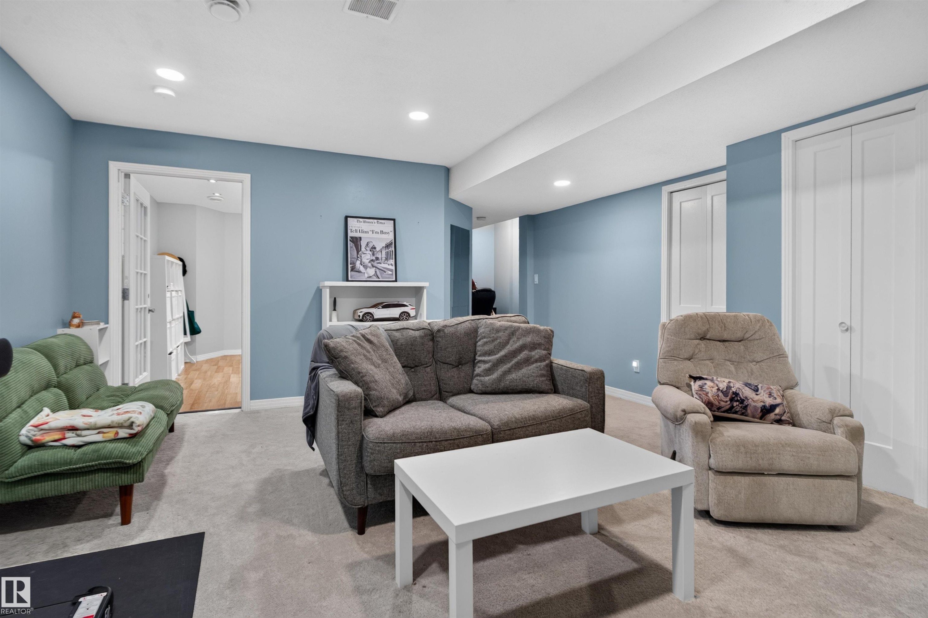 Recessed lighting, light blue wall paint, French doors, wood-finish flooring, and white bi-fold doors - 4471 Mccrae Avenue Nw, Edmonton, AB