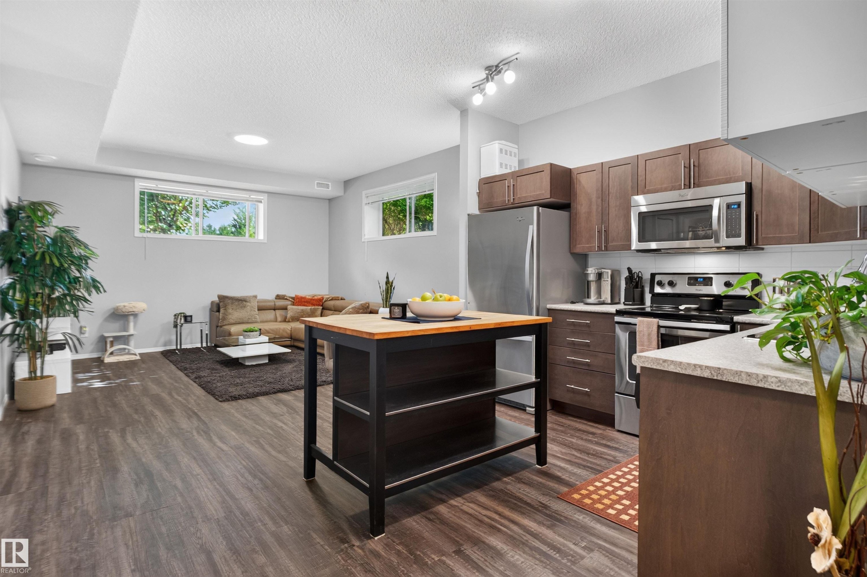 Modern kitchen featuring stainless steel appliances, wood-finish flooring, and light gray walls - #34 6520 2 Av Sw, Edmonton, AB - Indoor Photo Showing Kitchen With Stainless Steel Kitchen