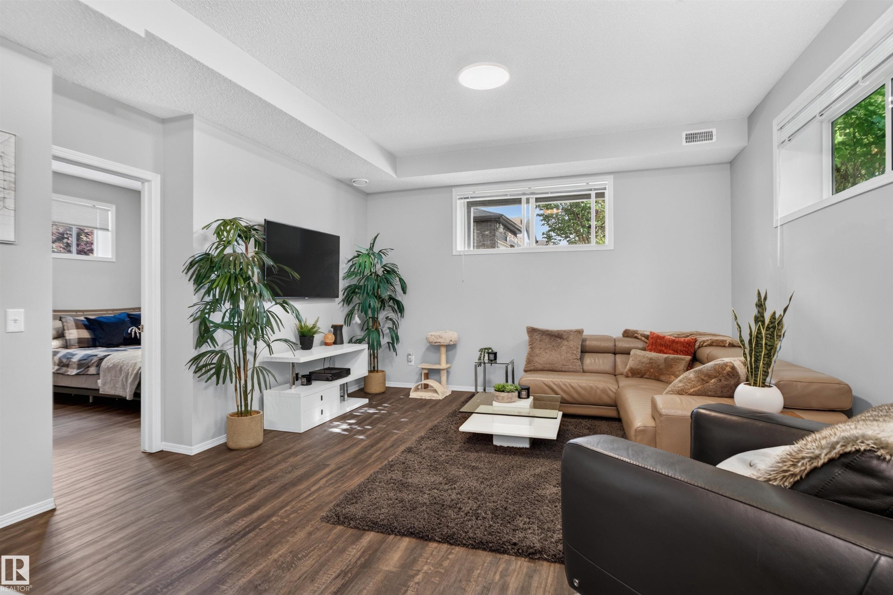 Wood-finish flooring throughout, light gray walls, white trim, and recessed lighting fixtures - #34 6520 2 Av Sw, Edmonton, AB - Indoor Photo Showing Living Room