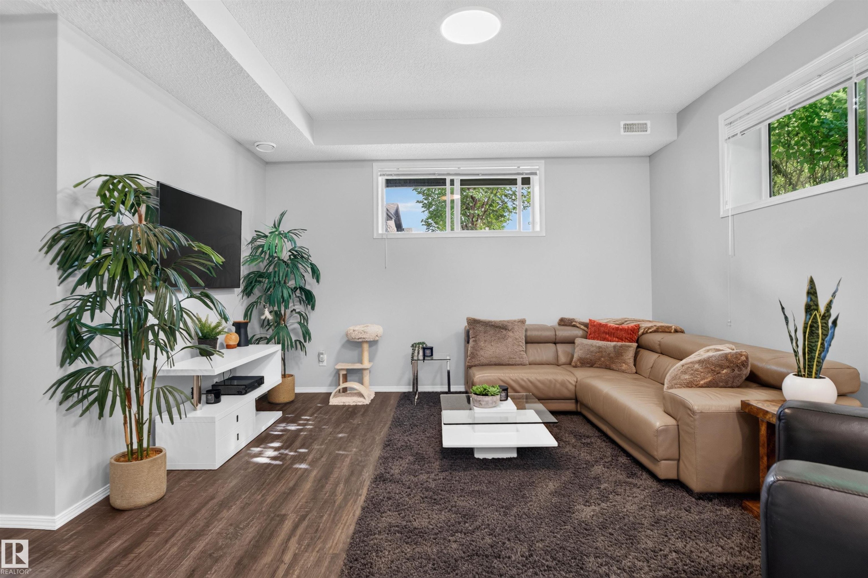 Wood-finish flooring, white trim, and light gray walls - #34 6520 2 Av Sw, Edmonton, AB - Indoor Photo Showing Living Room