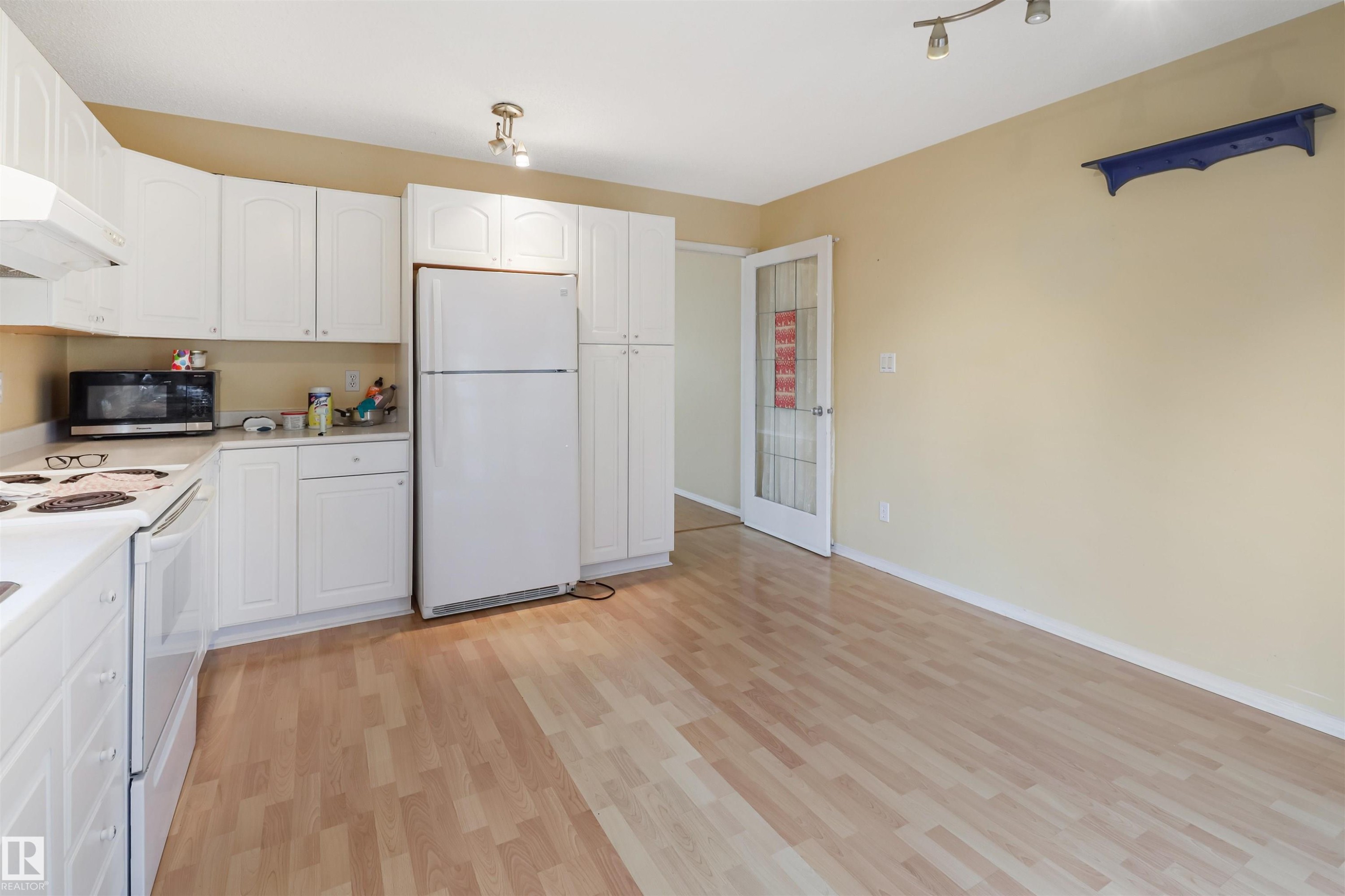 Kitchen featuring white cabinetry, wood-finish flooring, white appliances, and a track lighting fixture - 1055 Jones Crescent Nw, Edmonton, AB - Indoor Photo Showing Kitchen