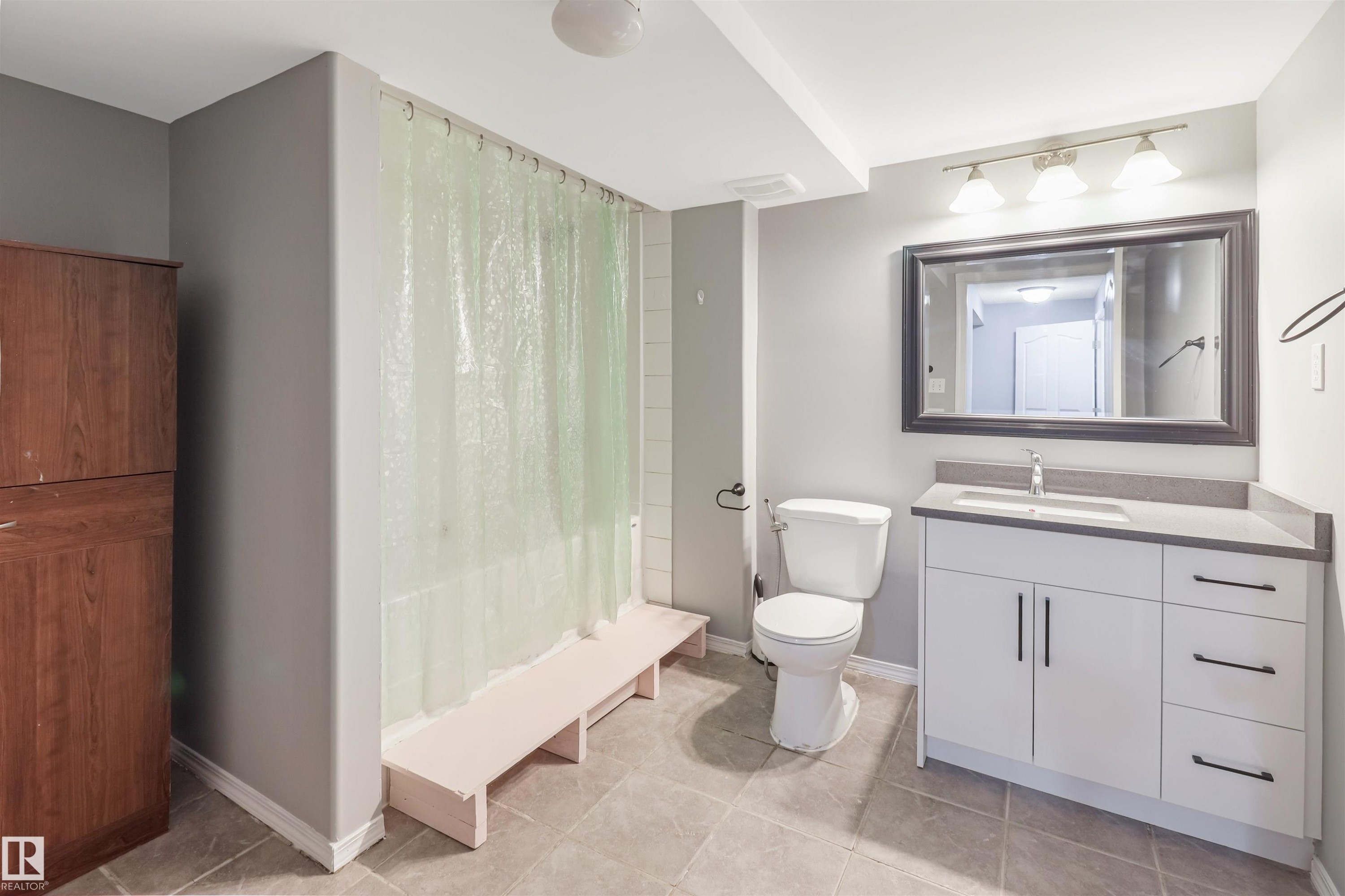 Spa-inspired primary bathroom featuring a frameless glass-enclosed shower with pale green tile surround, floating vanity with soft-close cabinetry and brushed nickel hardware, large illuminated mirror, and neutral tile flooring - 1055 Jones Crescent Nw, Edmonton, AB - Indoor Photo Showing Bathroom